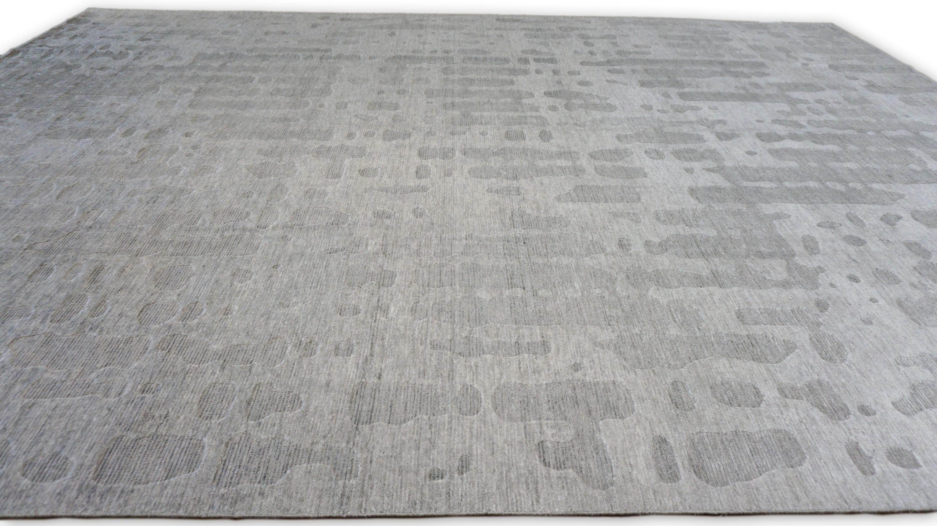 Questo elegante tappeto in cotone e viscosa lavorato a mano è un pezzo raffinato che unisce il design contemporaneo a una texture morbida e lussuosa. Il tappeto presenta un sofisticato motivo astratto in varie tonalità di grigio e taupe, creando un