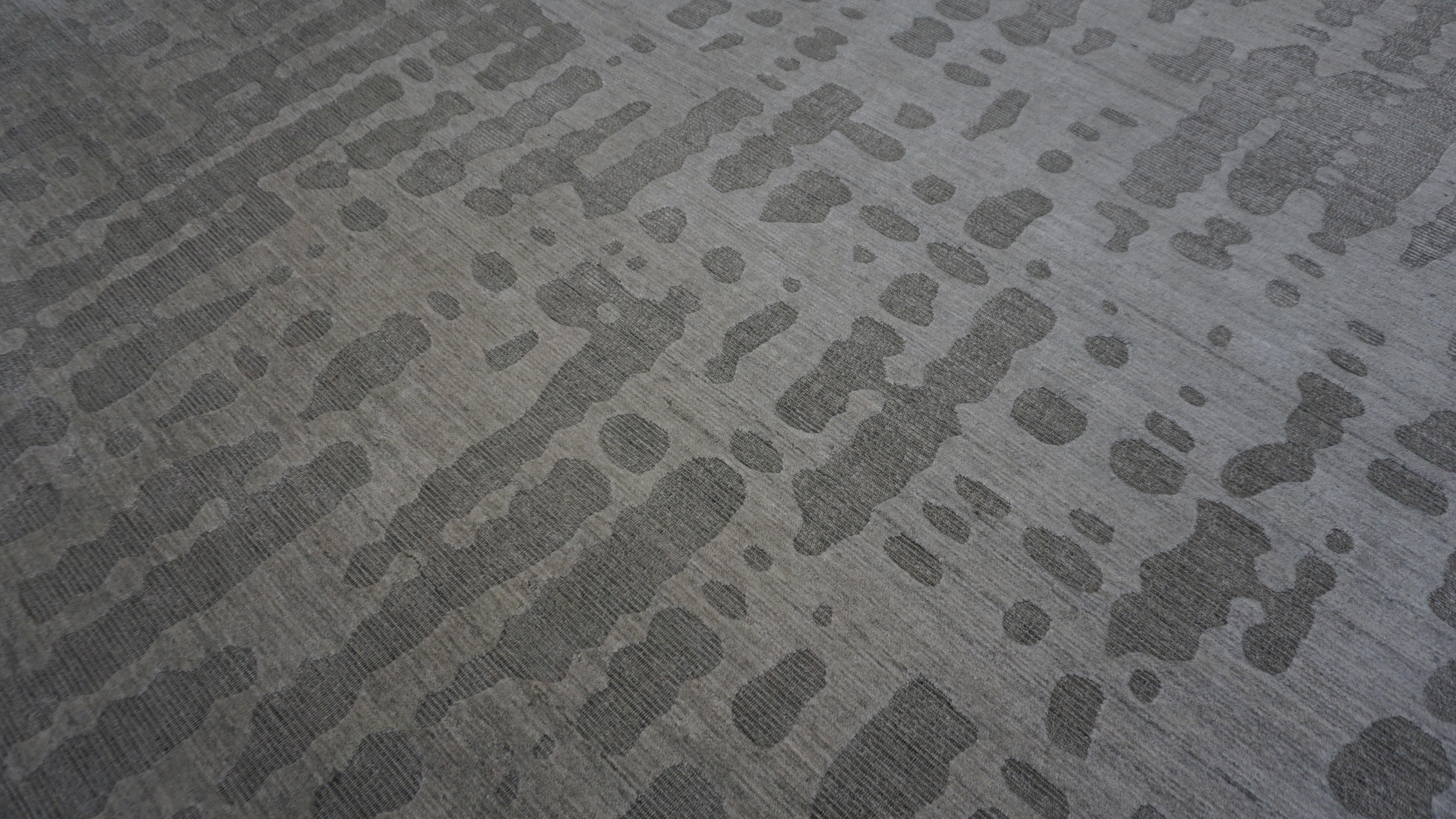 This contemporary handmade bamboo silk rug offers a sophisticated blend of tonal subtlety and modern surface design. Featuring an abstract, irregular dot-texture pattern, the motif is softly embedded into a smooth gray and taupe field with dark gray