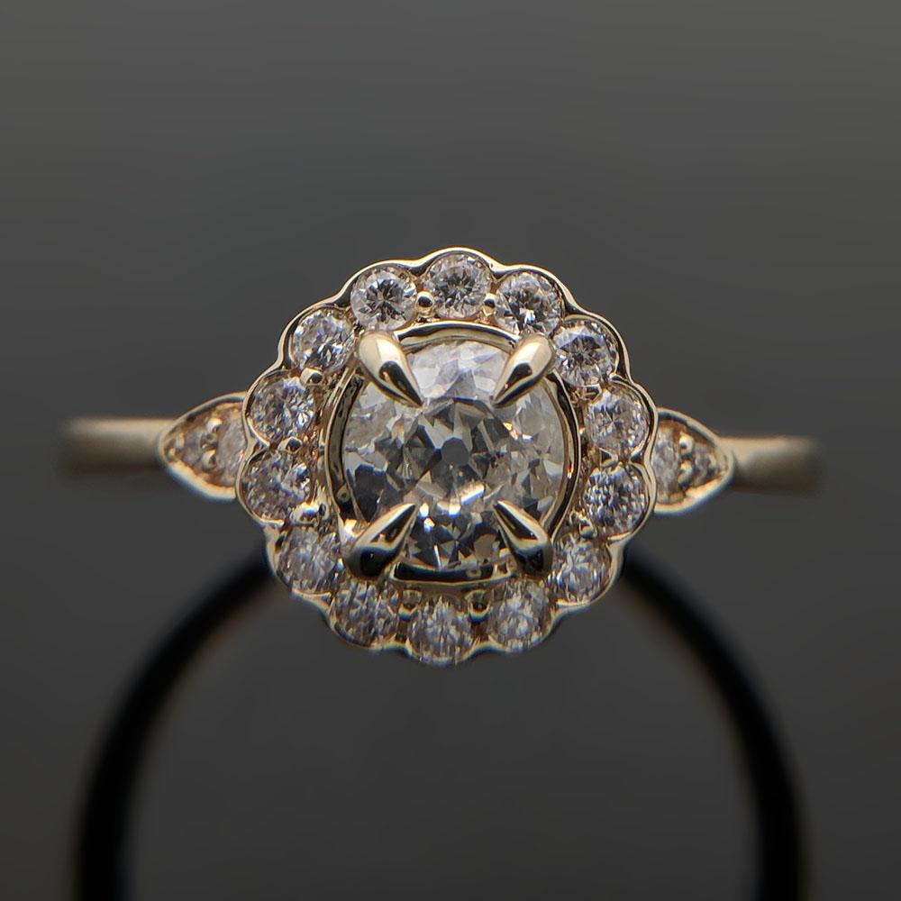 This is a low-profile 14kt yellow gold ring featuring a center diamond with an estimated weight of 0.45ct and 4 tapered prongs. Small diamonds with an estimated weight of  0.24cttw. encompass the center stone. Estimated weight of gold is 2 gr. 

We