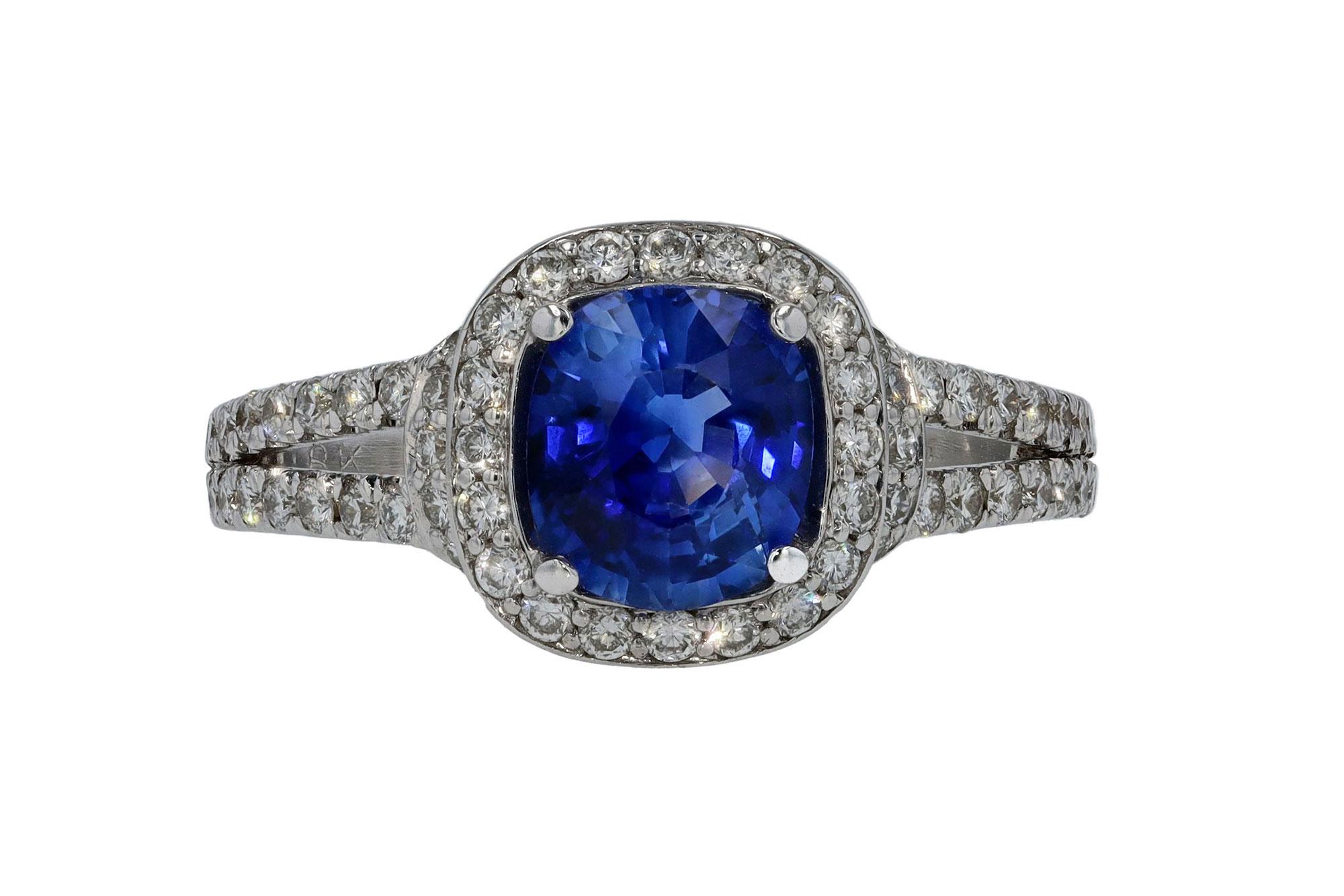 A contemporary sapphire and diamond engagement ring that commands attention. A 1.62 carat cushion cut sapphire is centered displaying a vibrant and deep blue. Accented by over 1 carat of shimmering, icy white diamonds forming the halo and open 