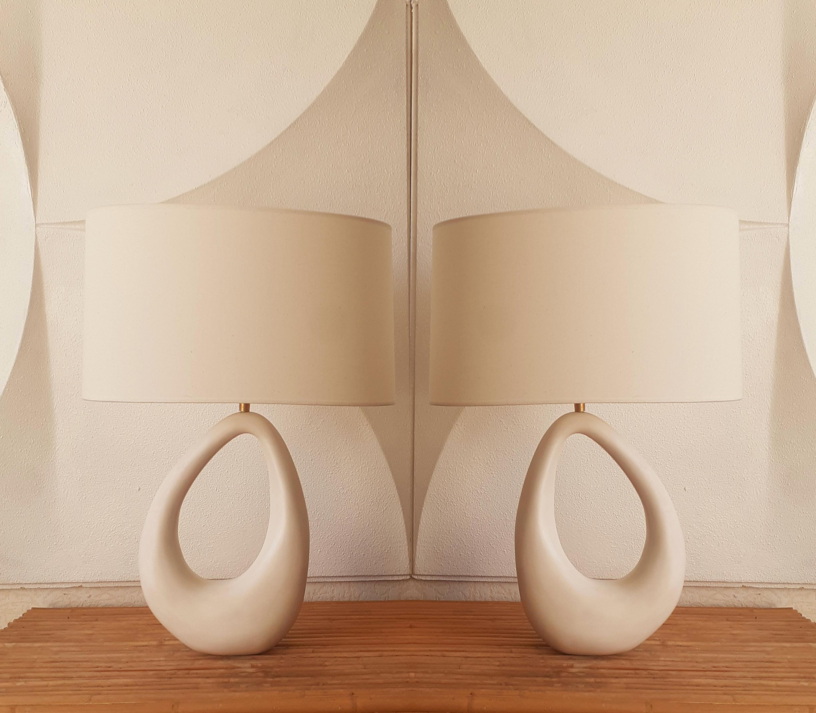 The base is made of biomorphic glazed ceramic, white satin color. 
Creamy white linen oval shade. Brass hardware.
Very decorative and sensual design.
EF Studio, Paris, France.

Pair of lamp available.
Price for 1 lamp with shade.

Measures: