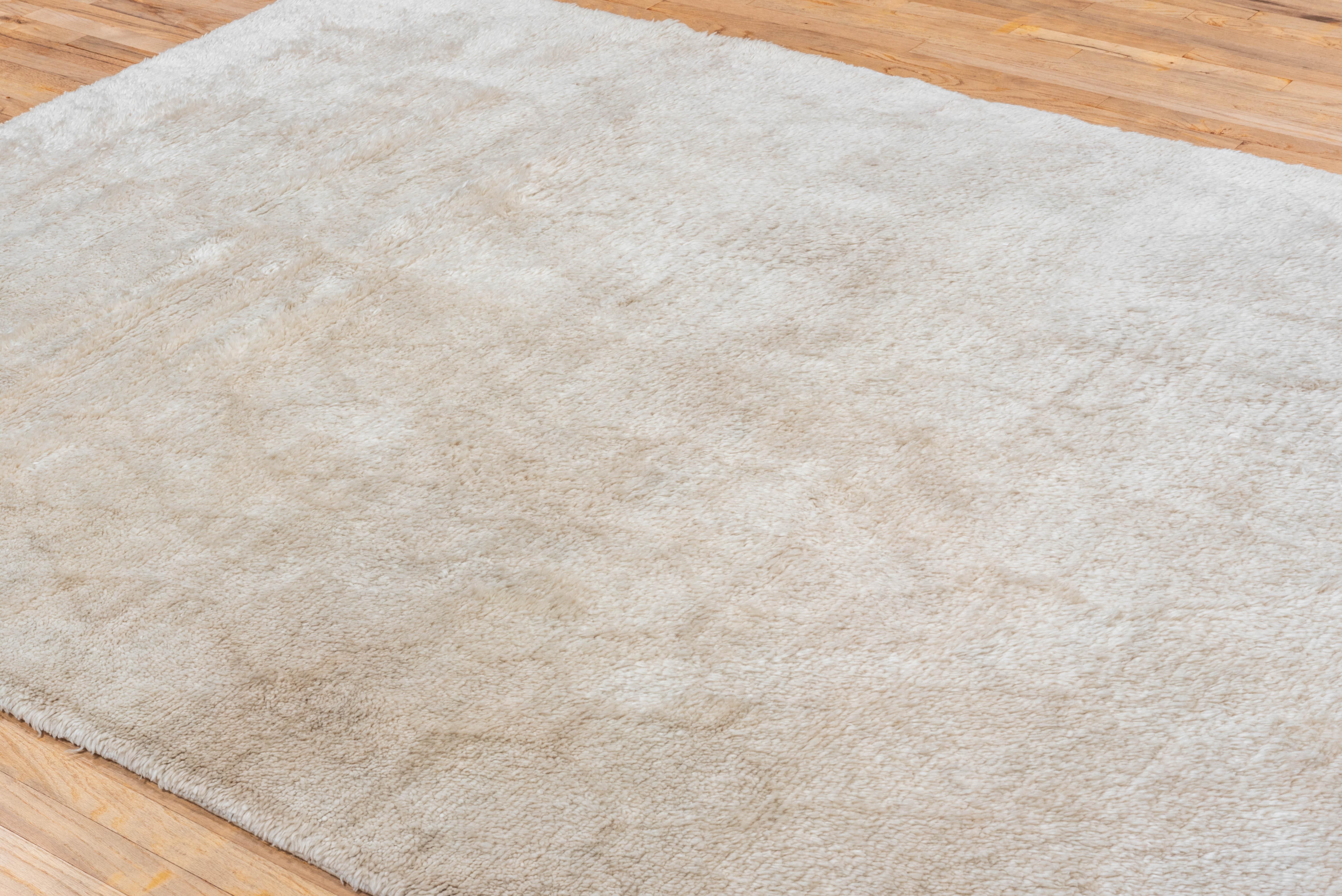 Elegant in its simplicity, this contemporary Moroccan rug is hand-knotted in plush ivory wool with a smooth, tonal surface. Its subtle variations in texture add depth while maintaining a soft, minimal aesthetic.