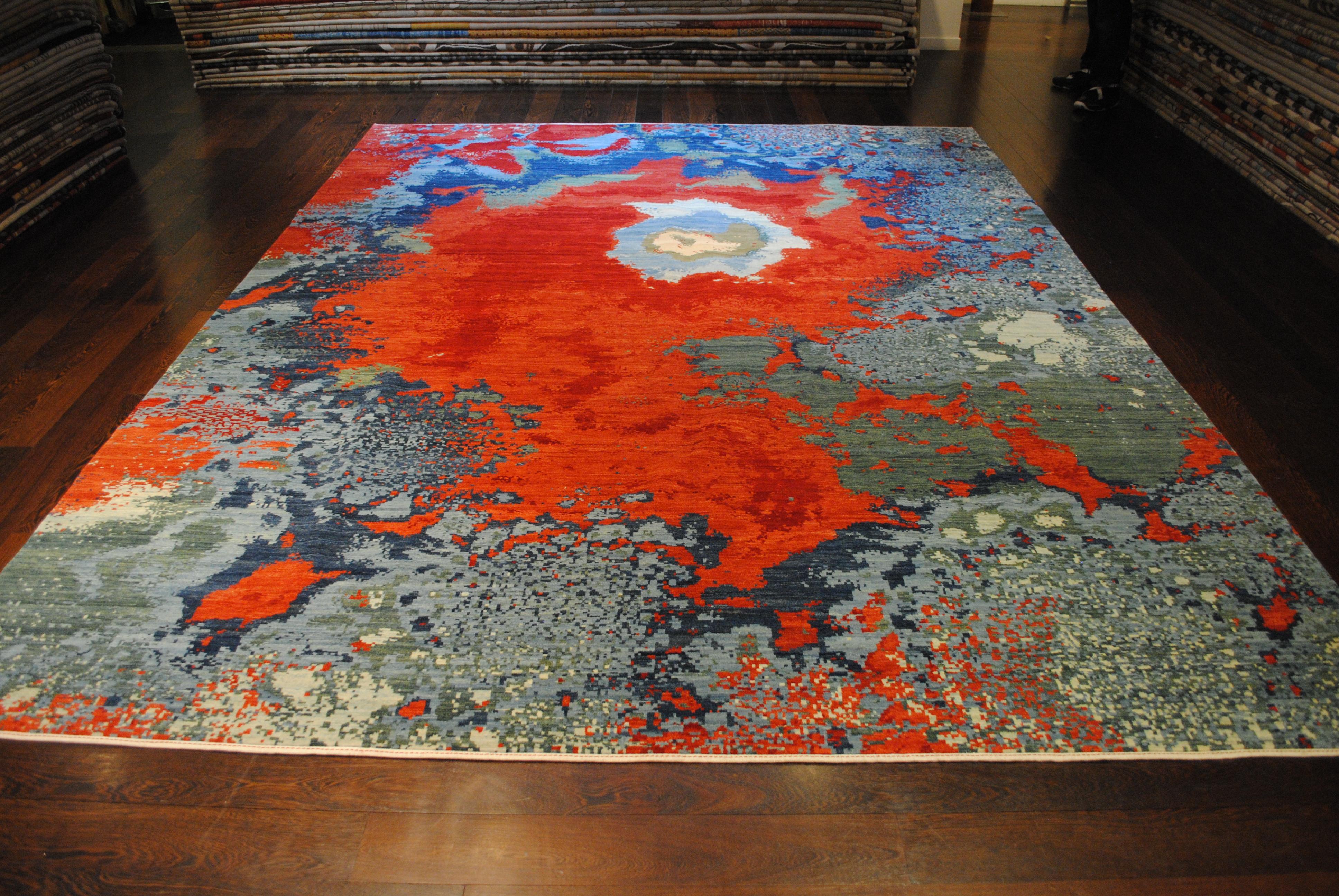 Bold, atmospheric, and richly expressive, “Magma” is a 9' x 12' hand-knotted wool rug inspired by the intense movement and energy of volcanic landscapes. Saturated reds flow across the surface like molten lava, while layers of blue, slate, and