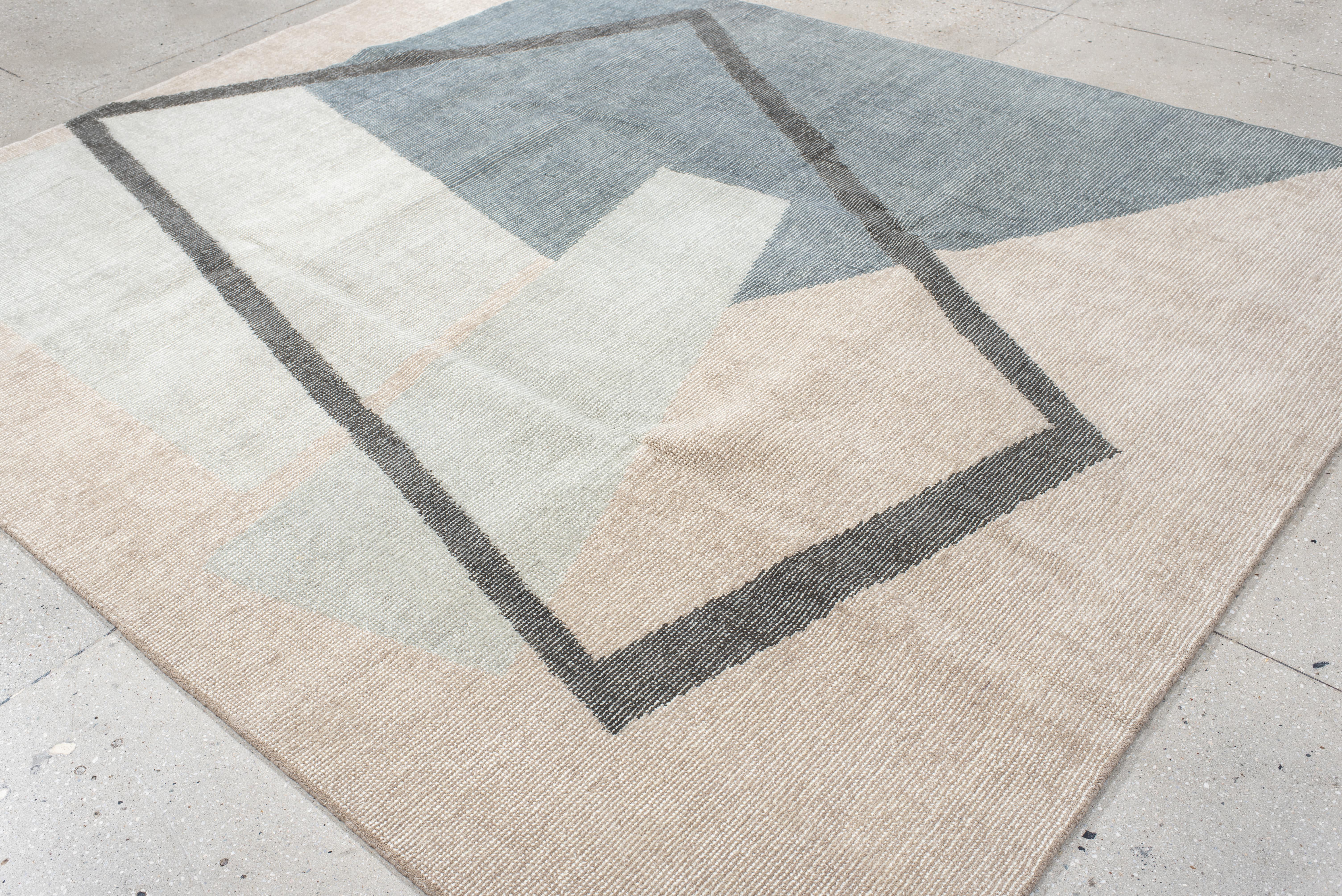 Dieser moderne, handgewebte Teppich zeigt eine auffällige geometrische Komposition mit geschichteten Formen in zartem Beige, hellem Mint und Schieferblau, die von einem kühnen, kantigen Rahmen in Holzkohle verankert werden. Das Design strahlt einen
