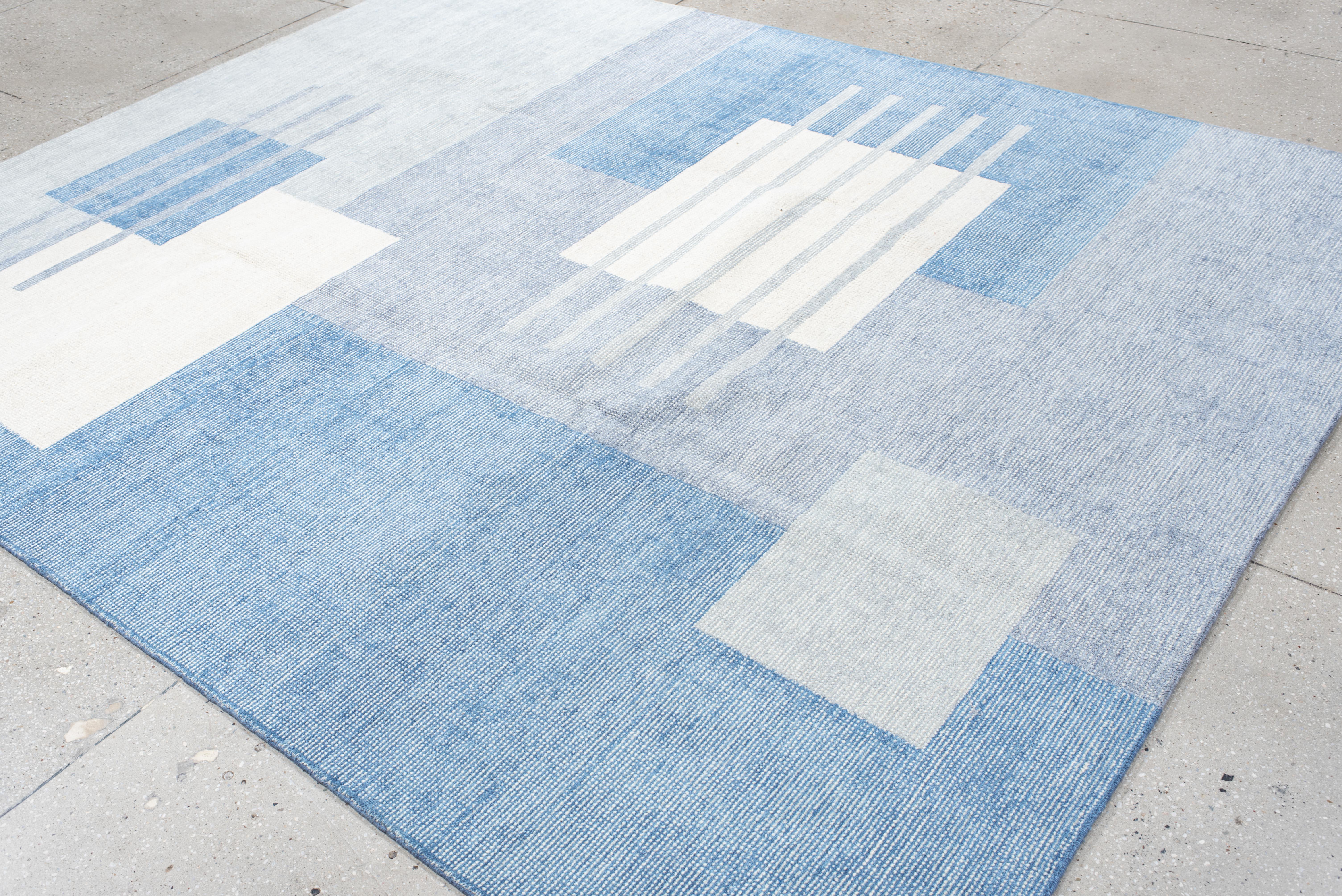 Questo tappeto contemporaneo lavorato a mano presenta un design pulito e architettonico composto da blocchi stratificati e linee orizzontali in azzurro, avorio e acciaio chiaro. La composizione minimalista strizza l'occhio alle influenze della metà