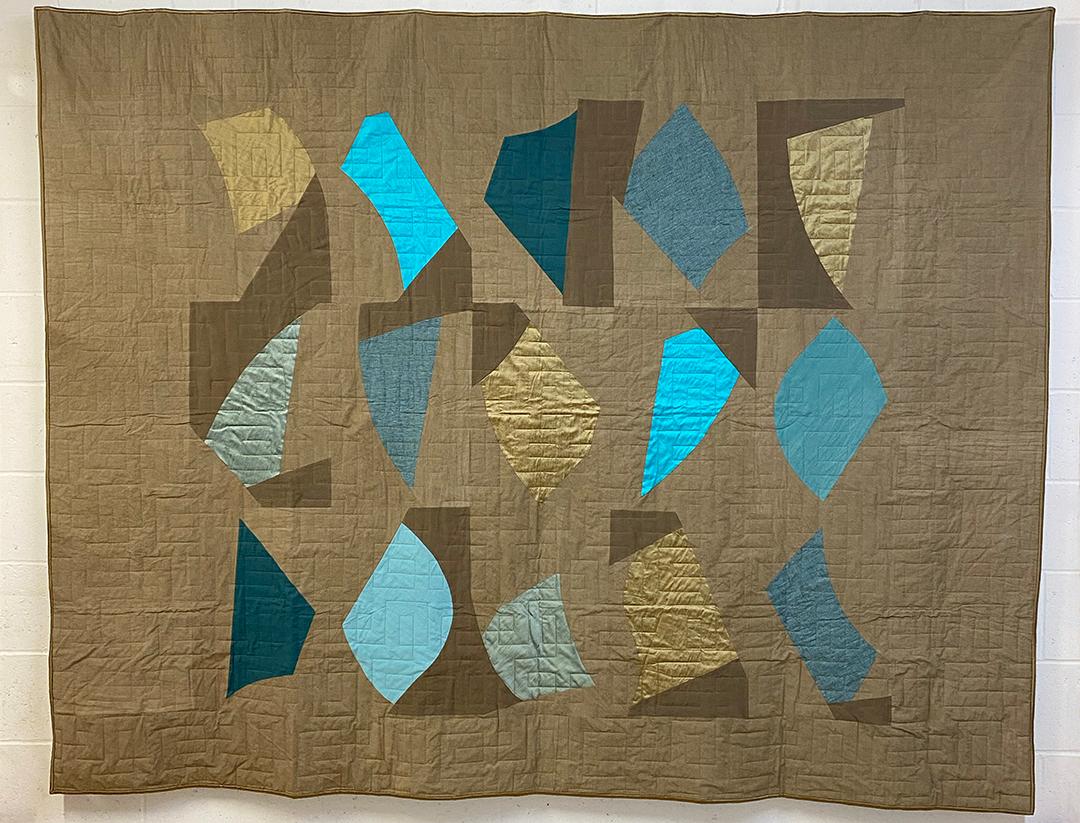'Fragments' quilt in Blues colourway by British artist-maker, Emily Campbell. Emily’s knowledge of sewing combines with the formal and visual principles she learned as a two-dimensional designer to re-imagine the patchwork quilt. She has interpreted