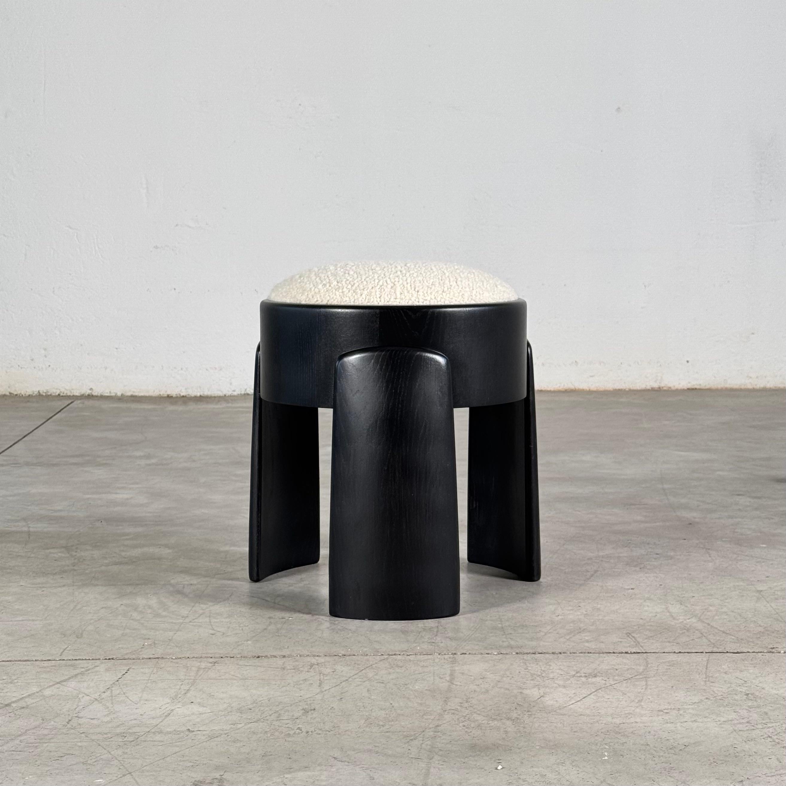 Ein skulpturales Gleichgewicht aus Geometrie und taktiler Raffinesse. Dieser maßgefertigte Hocker interpretiert die Materialität mit einer neuen Nuance von Licht und Textur neu.

Der Sockel ist aus massivem Eschenholz gefertigt, das in einem tiefen,