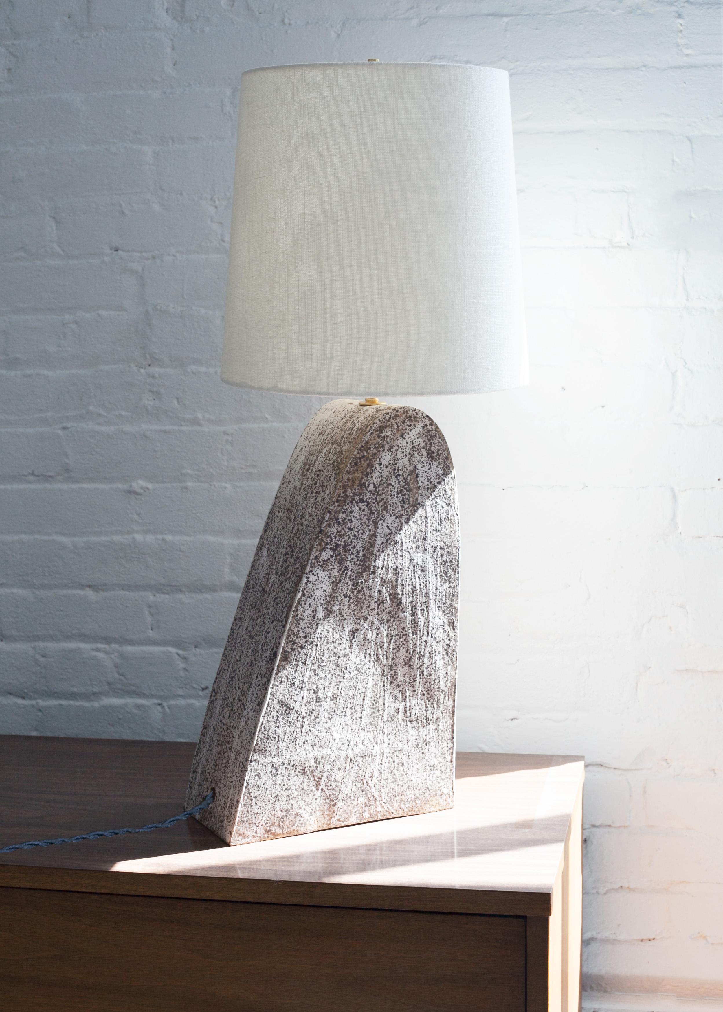 Einzigartige Keramiklampe, einzigartig und handgefertigt. Der Lampenfuß besteht aus gesprenkeltem Steinzeugton mit mattweißer Glasur. Dieses Stück wurde von Muscheln und glatten Steinen inspiriert, die auf Reisen nach Neuengland am Strand gesammelt