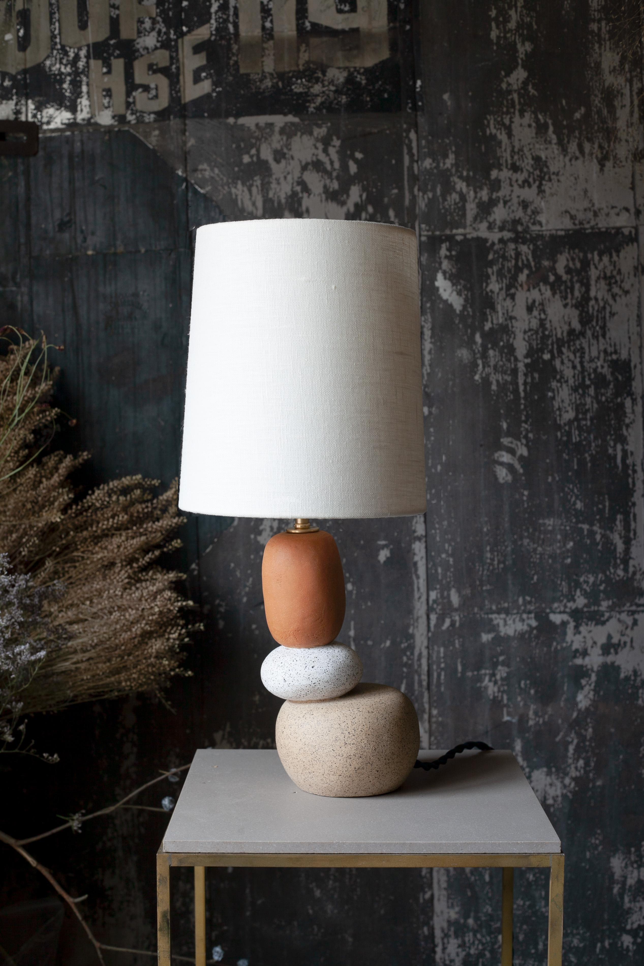 One of a kind ceramic lamp, thrown on the potters wheel and assembled by hand. The lamp base is comprised of two different clay bodies that celebrate the texture of unglazed ceramic. This piece was inspired by seashells and smooth stones collected