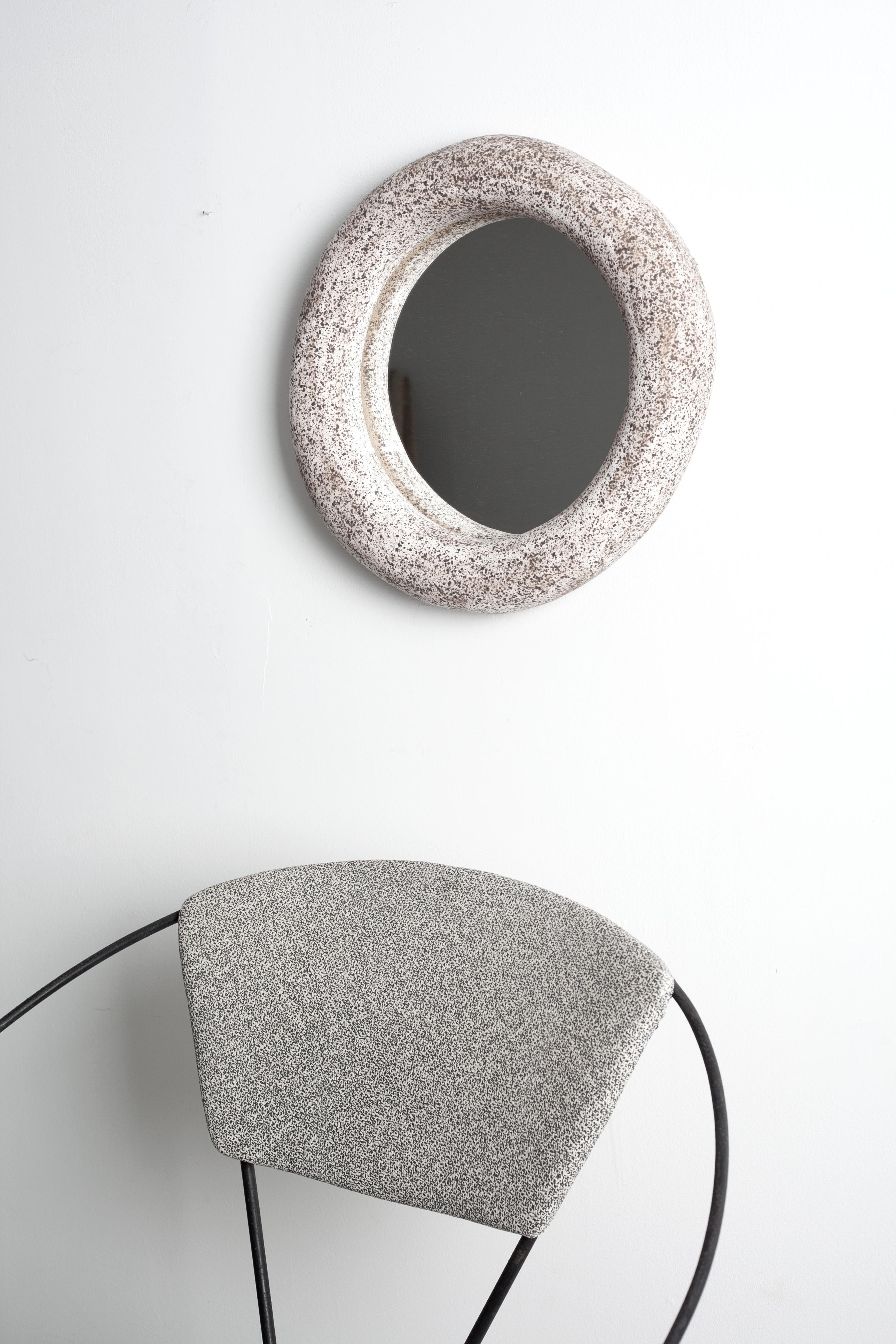 One of a kind ceramic mirror, unique and hand built. The mirror frame is comprised of speckled stoneware clay with matte white glaze. 
Diameter measures 15” and is about 4” deep. The back has two 3/4” holes for easy hanging and is finished with soft