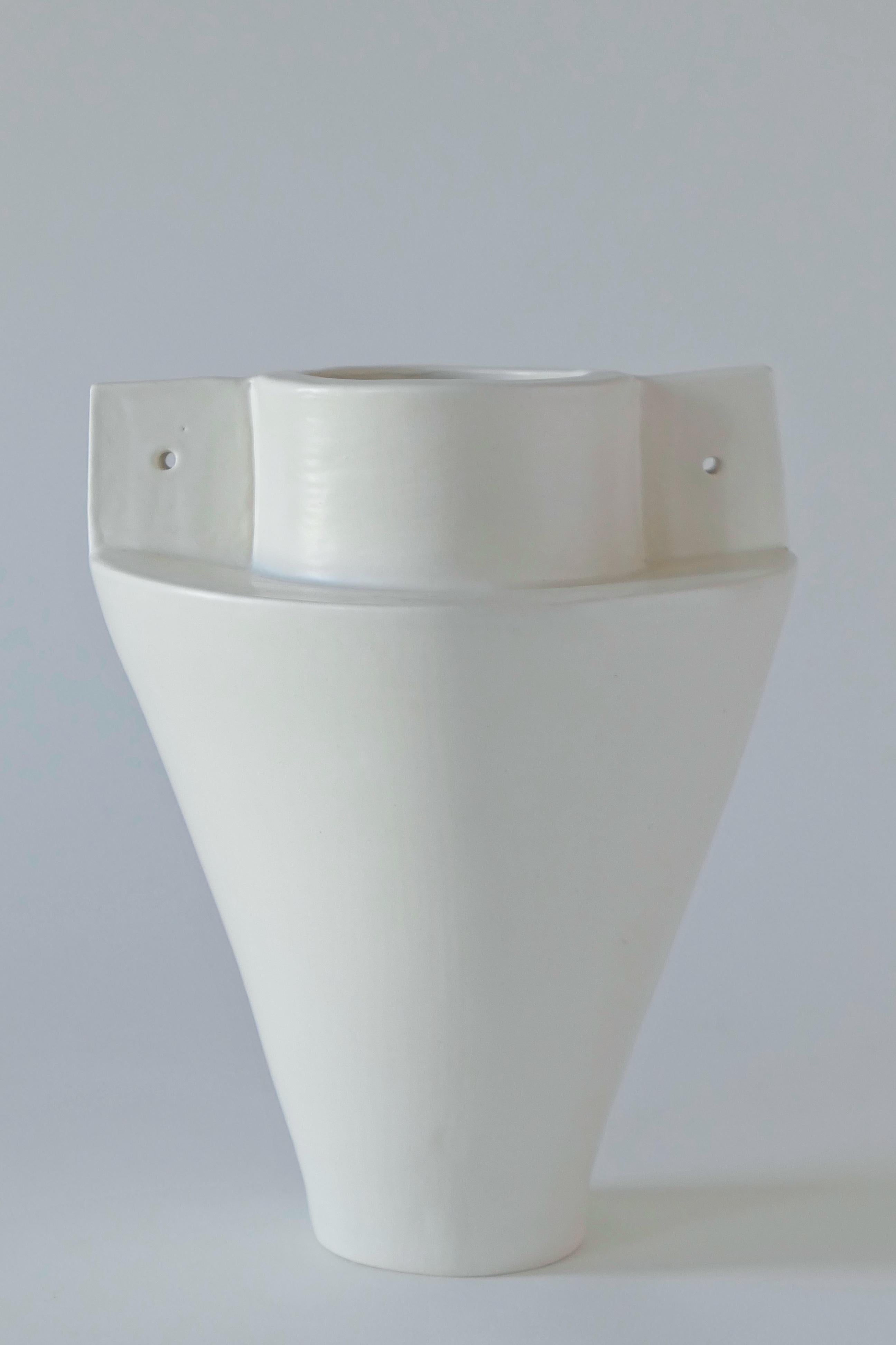 White stoneware vase, finished with a soft, white glaze. This vase is built by hand using clay slabs.

Karina Vieira is a Brooklyn-based ceramicist focusing on handbuilt vessels. 

Her work references various styles, touching on the