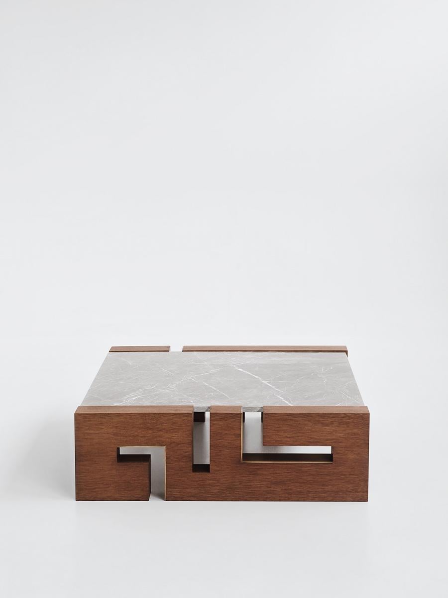 Table basse contemporaine faite à la main A avec un plateau rectangulaire en marbre posé sur deux socles en bois massif, aux formes géométriques.
Des variations sont possibles en termes de taille, de type de marbre, de type et de finition du bois,