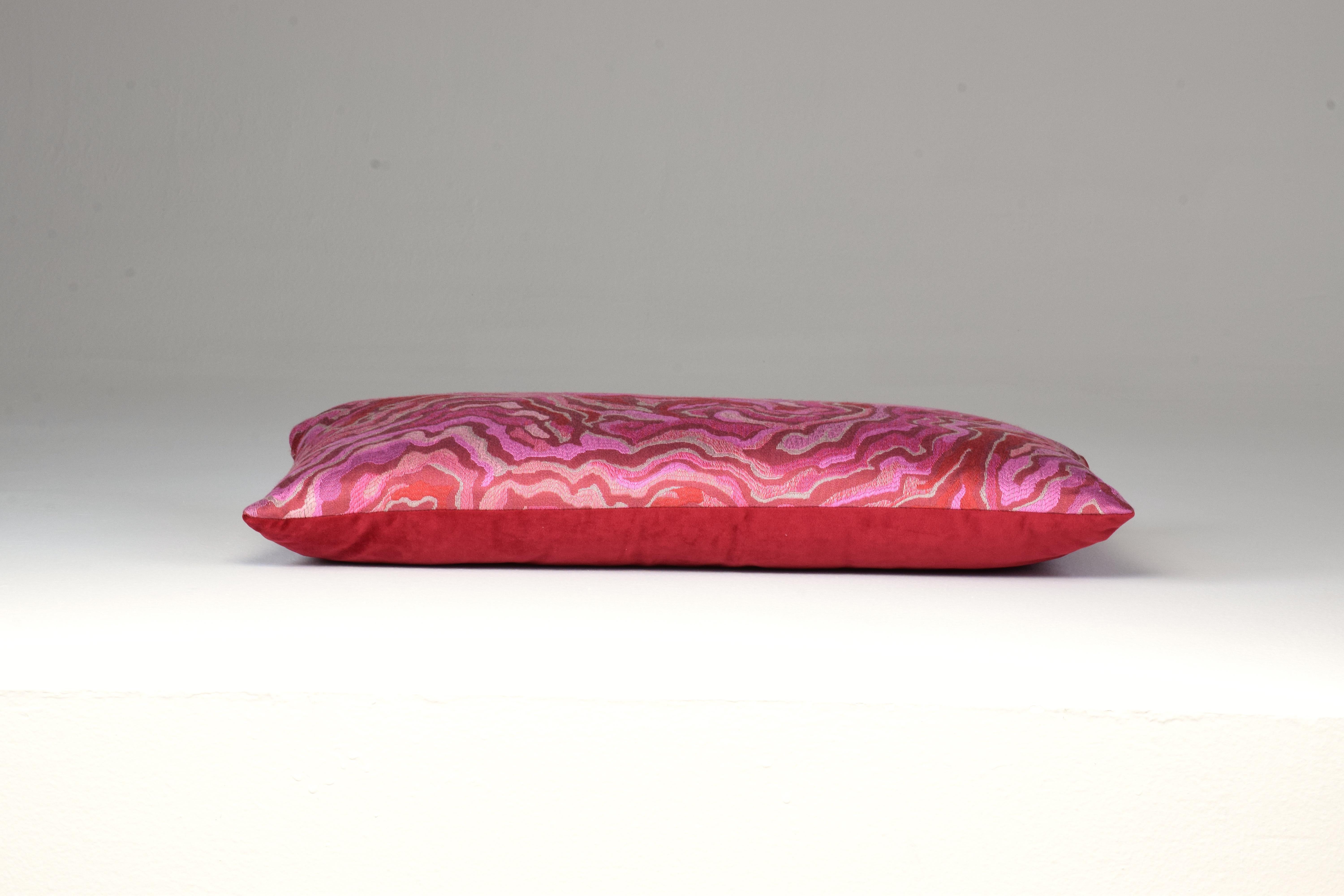 A rectangular cushion with embossed wool and cotton weaving and wave-shaped patterns in a beautiful palette of pink colors on the front side, and strawberry velvet on the backside. This pillow will elevate the mood of your bedroom and your living