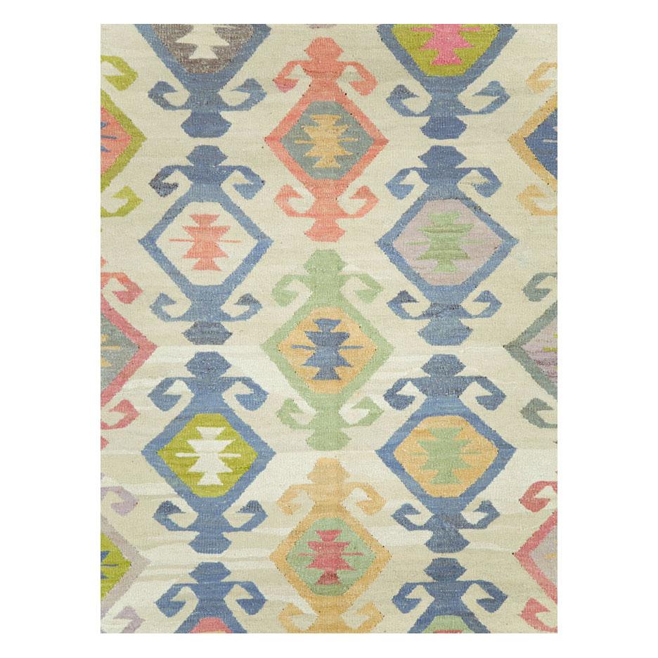 A modern Turkish Kilim flat-weave room size rug handmade during the 21st century with a beige background and grey border. The all-over design is comprised of pastel colors including blue, pink, and green.

Measures: 10' 1