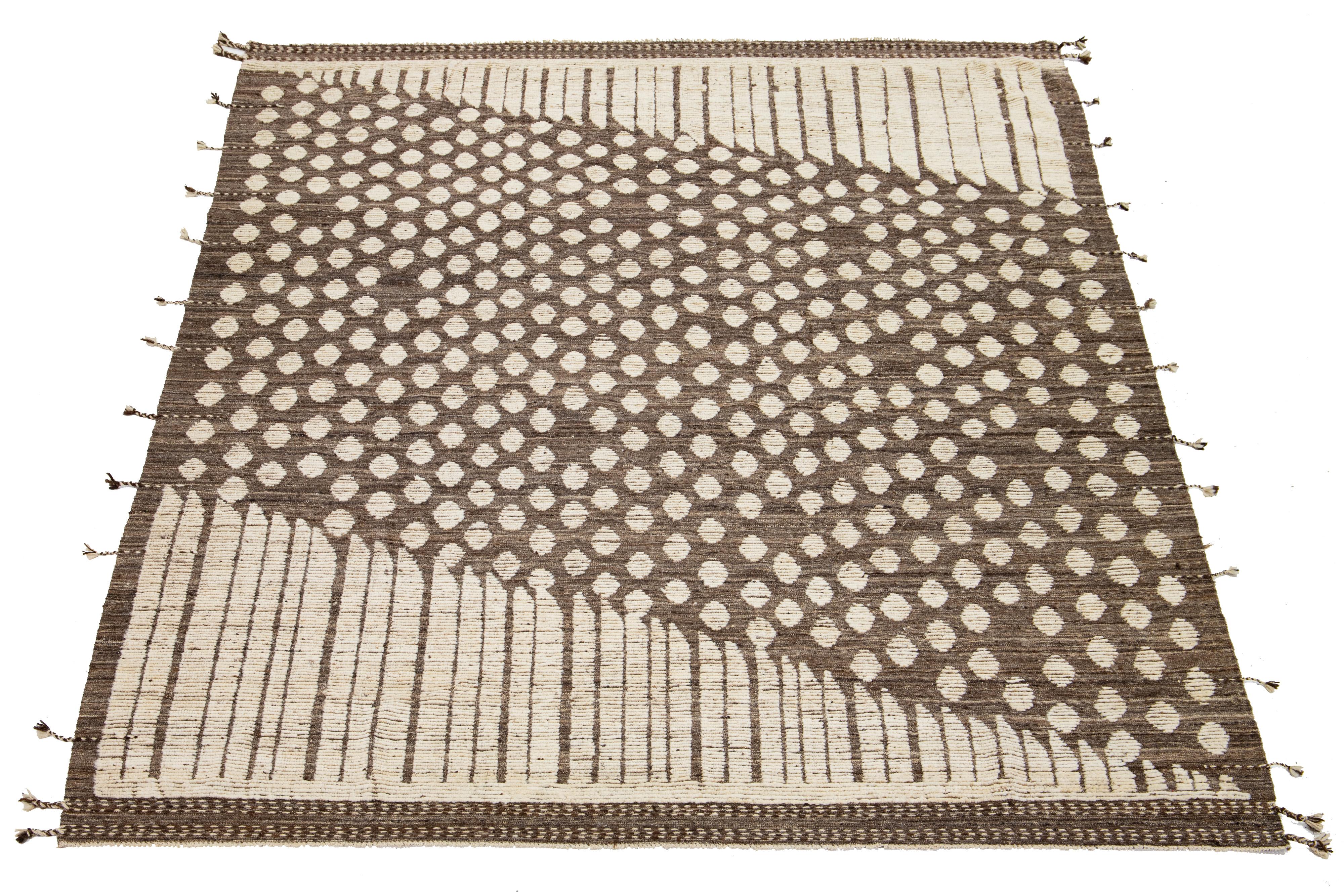 Questo bellissimo tappeto in lana realizzato a mano presenta uno stile marocchino contemporaneo con un sorprendente sfondo marrone e grigio. Presenta moderni disegni geometrici in un mix di beige davvero accattivante.

Questo tappeto misura 9'5