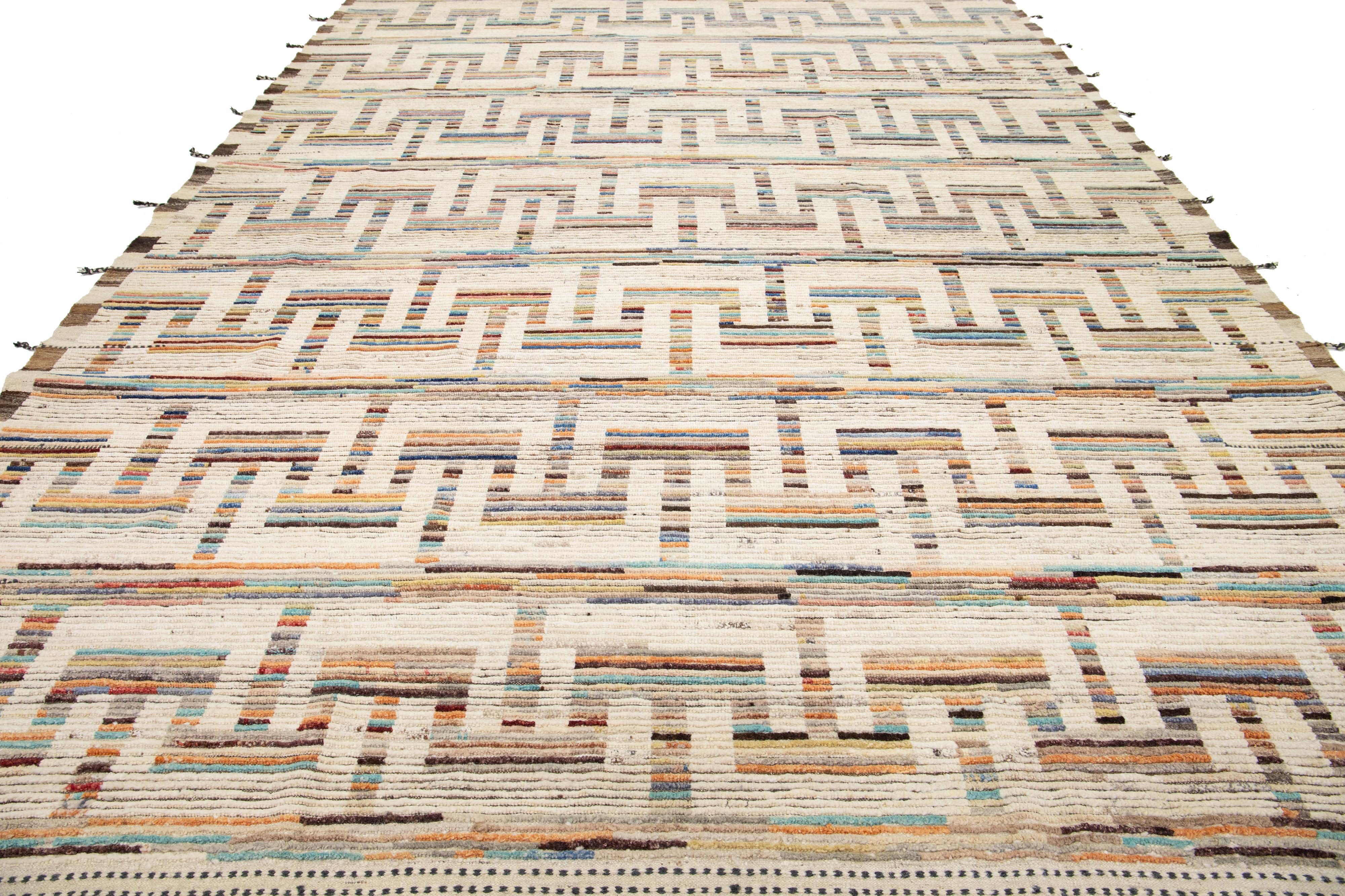 Questo tappeto in lana, realizzato a mano, presenta uno stile marocchino contemporaneo, evidenziato da un accattivante sfondo beige. Presenta moderni disegni geometrici in una miscela di colori vivaci che si fanno notare.

Questo tappeto misura