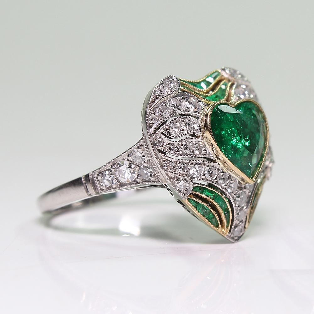 Period: Art Deco (1920-1935)
Composition: Platinum

Stones:
•	1 natural Colombian heart shape emeralds that weighs 1ctw.
•	23 natural calibrated cut emeralds that weigh 0.75ctw.
•	50 Single cut diamonds of G-VS2 quality that weigh 0.75ctw. 
Ring