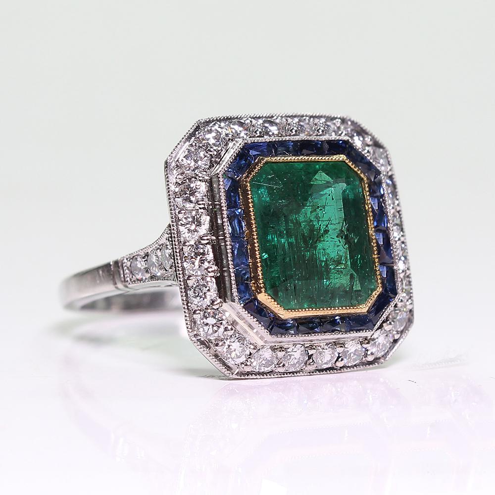 Composition: Platinum

Stones:
·      1 natural Colombian cut emerald that weighs 3ctw.
·      32 Full cut diamonds of H-VS2 quality that weigh 0.75ctw.
·      20 natural calibrated French cut sapphires that weigh 1ctw.

Ring face:  16mm by