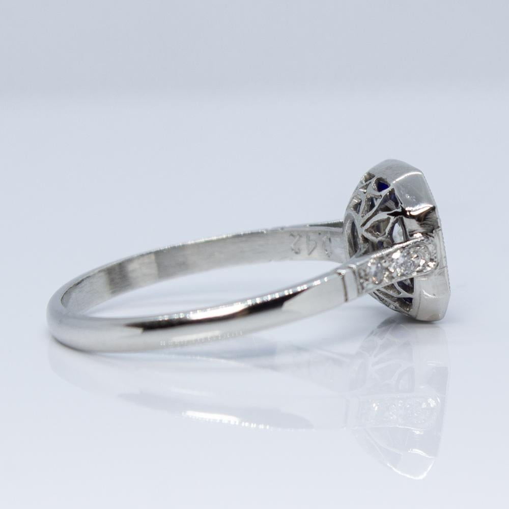 Composition: Platinum
Stones:
•	1 Old mine cut diamond of H-VS2 quality that weighs 0.45ctw. 
•	4 Old mine cut diamonds of H-VS2 quality that weigh 0.04ctw.
•	16 natural calibrated cut sapphires that weigh 0.80ctw.
Ring size: 7   
Ring face:  10mm