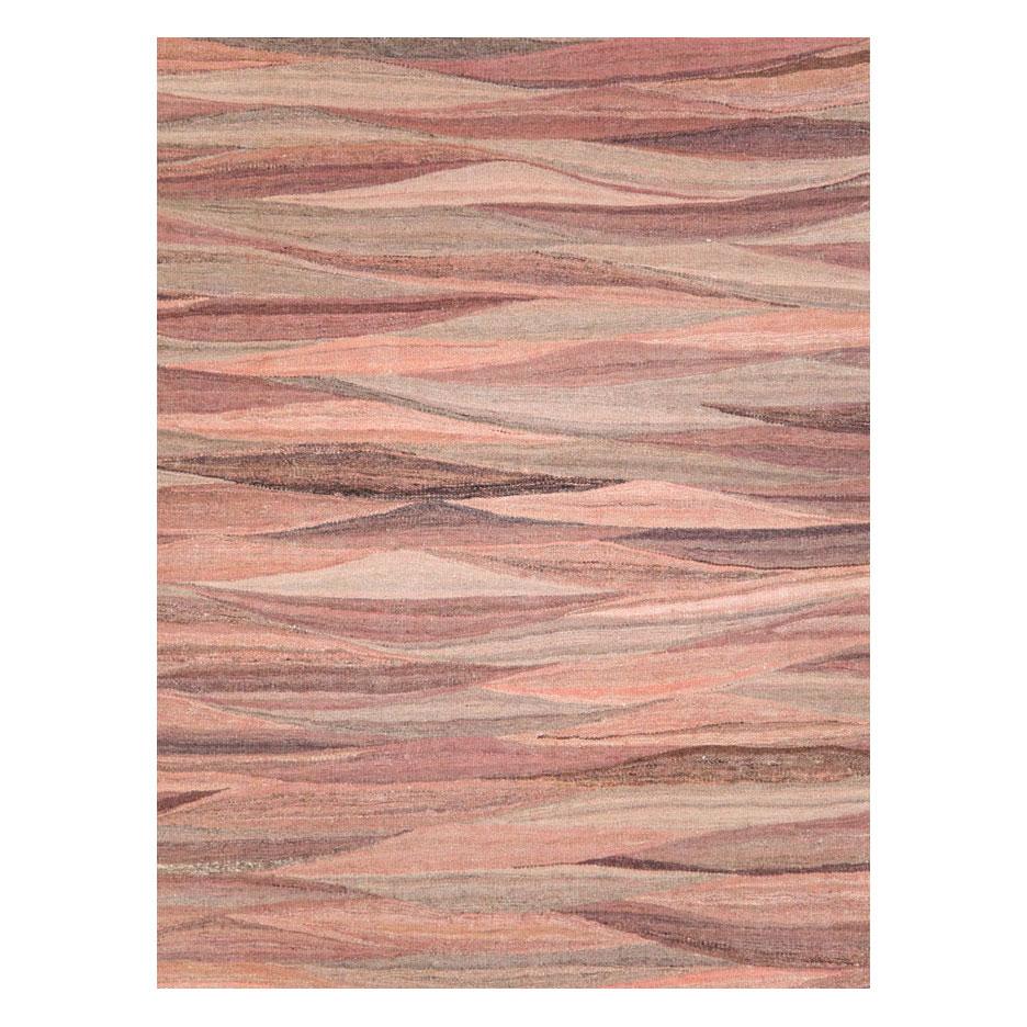 A modern Turkish flat-weave Kilim room size rug handmade during the 21st century. Various shades of pink ranging from 'New York Pink' to 'Pastel Pink' striate across the ground of the Swedish inspired curvilinear tapestry weaving