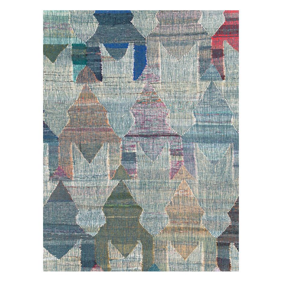 A modern Turkish flat-weave Kilim large room size carpet handmade during the 21st century with a geometric large scale pattern resembling circus tents over a bluish-grey background.

Measures: 12' 7