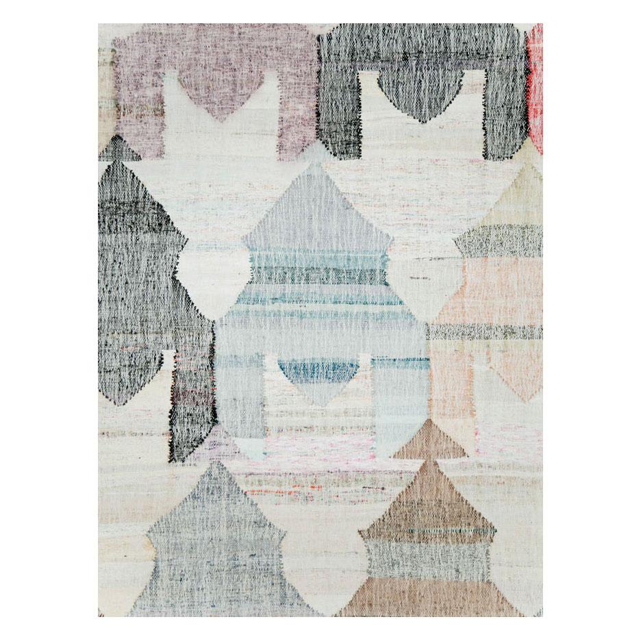 A modern Turkish flat-weave Kilim large room size carpet handmade during the 21st century with a neutral pastel colored geometric large scale pattern resembling circus tents over a white background.

Measures: 13' 6