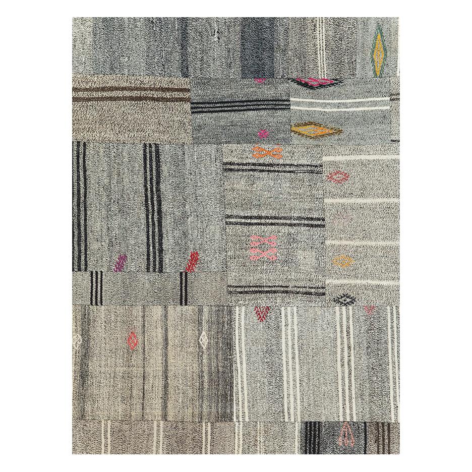 A contemporary Turkish flatweave Kilim room size rug handmade during the 21st century with a salt and pepper effect that gives off a predominantly grey appeal. Tribal design elements are scattered throughout the rug in colorful shades. This rustic