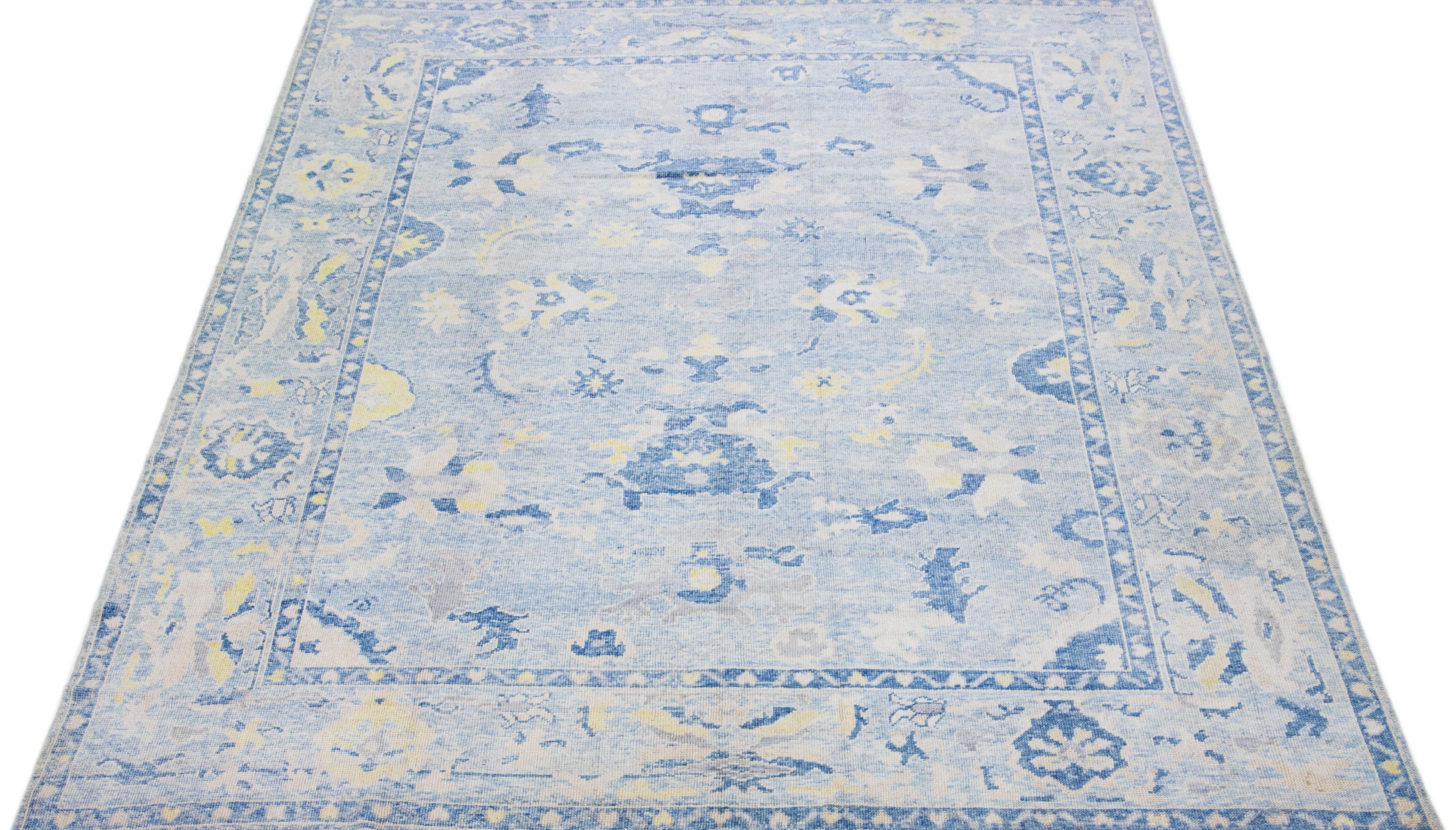Beautiful modern Oushak hand-knotted wool rug with a blue color field. This Turkish Piece has beige, gray, and yellow accent colors in a gorgeous all-over floral design.

This rug measures: 9'9