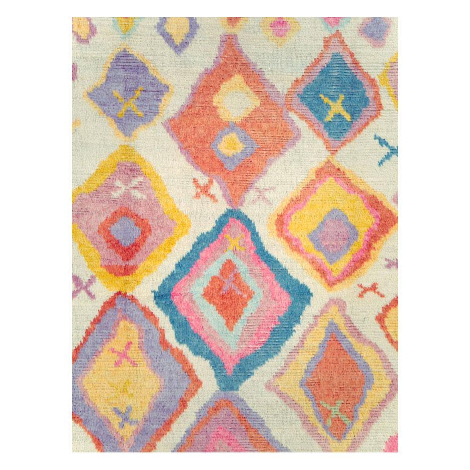 A modern Turkish Tulu room size rug handmade during the 21st century with a whimsical pattern in cheerful bright colors over a cream white background.

Measures: 8' 11