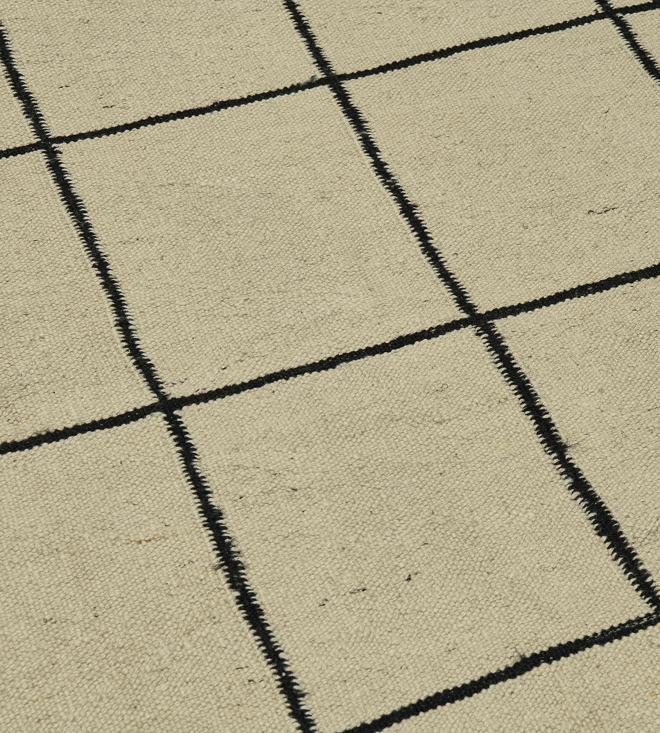 This minimalist, contemporary flatweave rug is seamlessly woven in hemp. The muted beige background sharply contrasted with a restrained latticework grid design. The sophisticated and versatile nature of this classic windowpane design lets this 5’2”