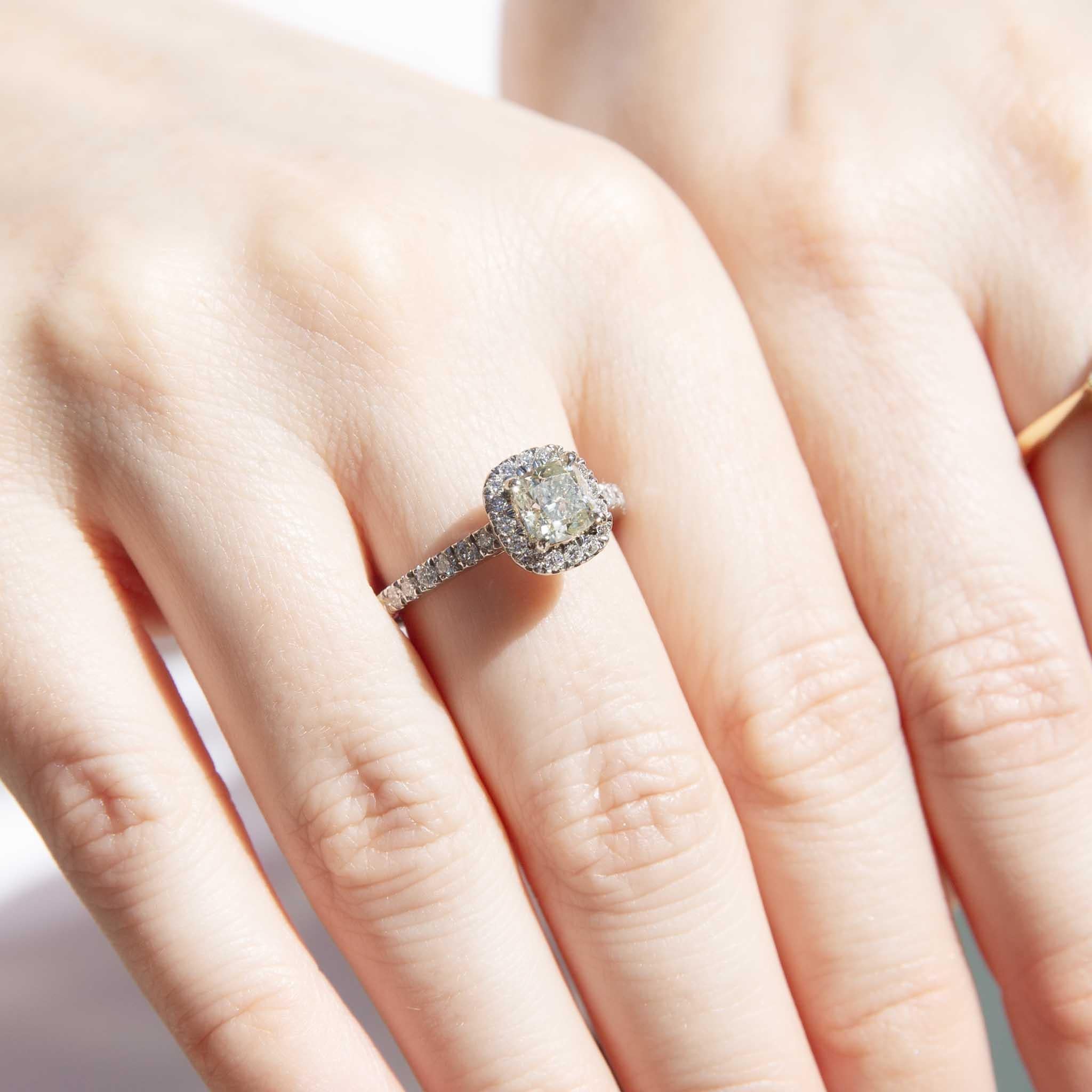 Il nostro splendido anello Soniqa in platino contiene un'incantevole quantità di diamanti pari a 1,60 carati: il diamante centrale con taglio a cuscino certificato IGI si trova all'interno di un'aureola di diamanti più piccoli e di altri diamanti