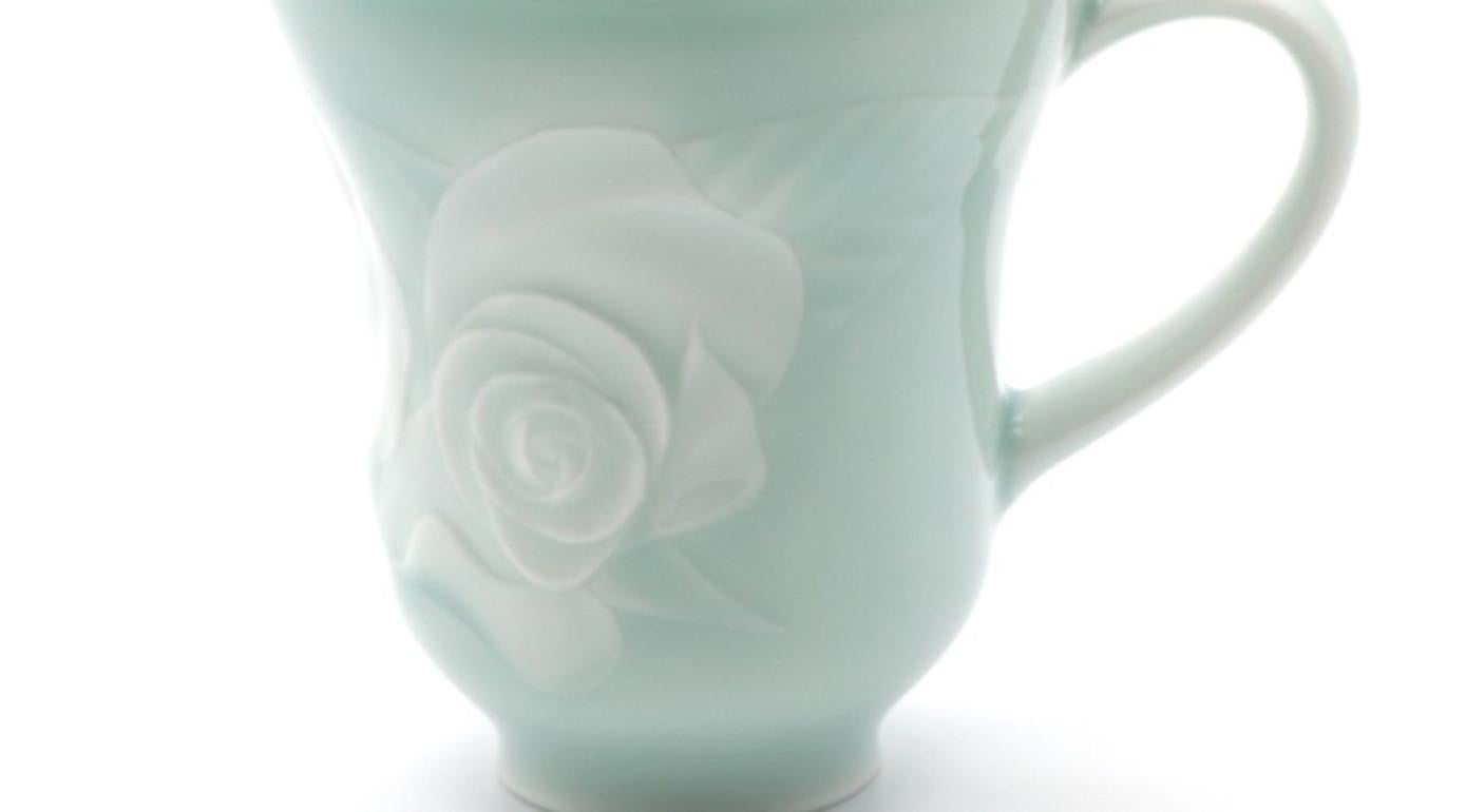 This stunning contemporary Imari porcelain mug in a soft blue white color with an elegant raised rose emerging from the surface, is a work of an Imari porcelain artist. He uses the traditional “intaglio” technique to create mesmerizing pieces with