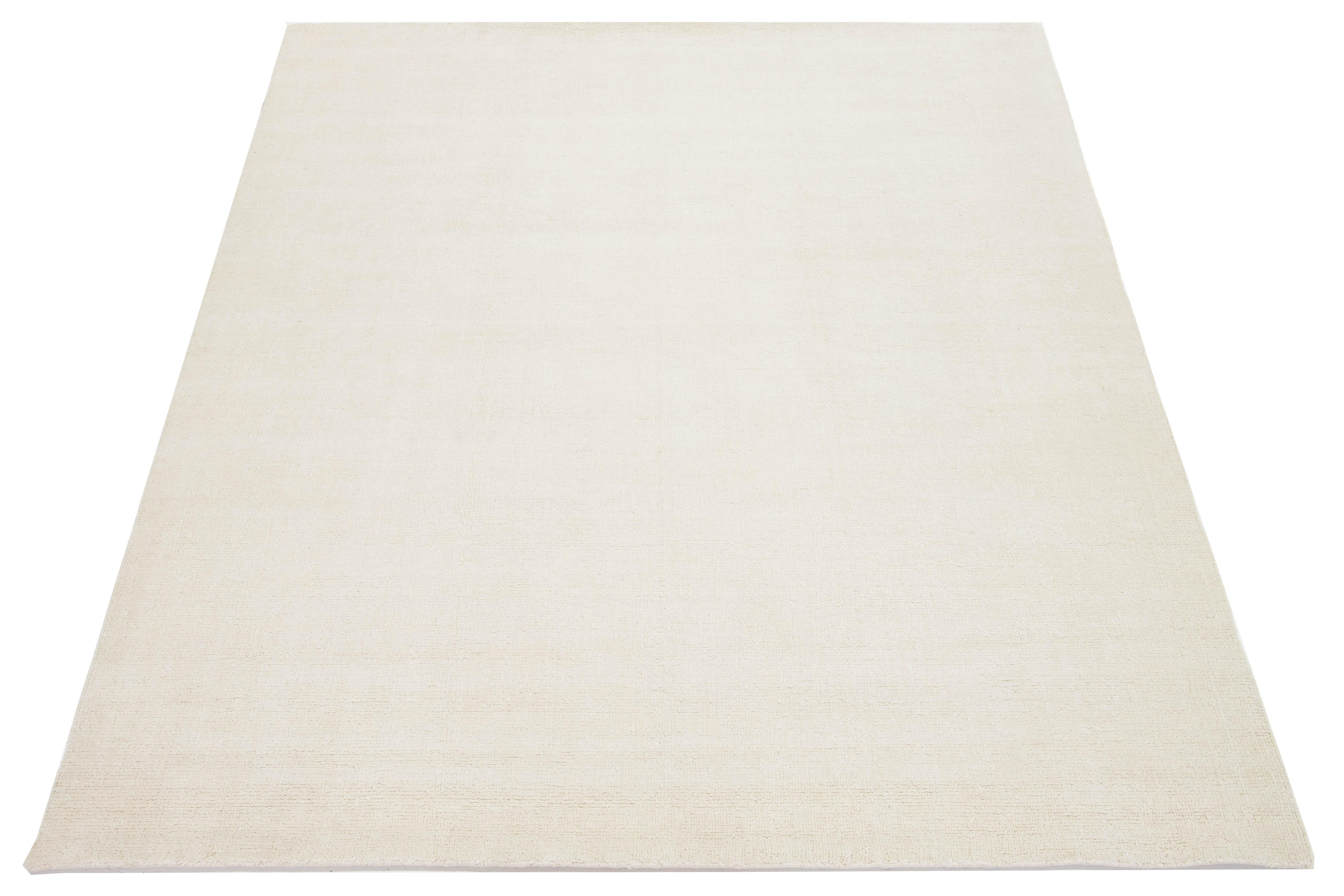 Esta moderna alfombra india de lana anudada a mano ha sido elaborada por expertos artesanos y presenta un diseño limpio. Su suave color marfil actúa como telón de fondo versátil, permitiendo que armonice sin esfuerzo con una gama de estilos de
