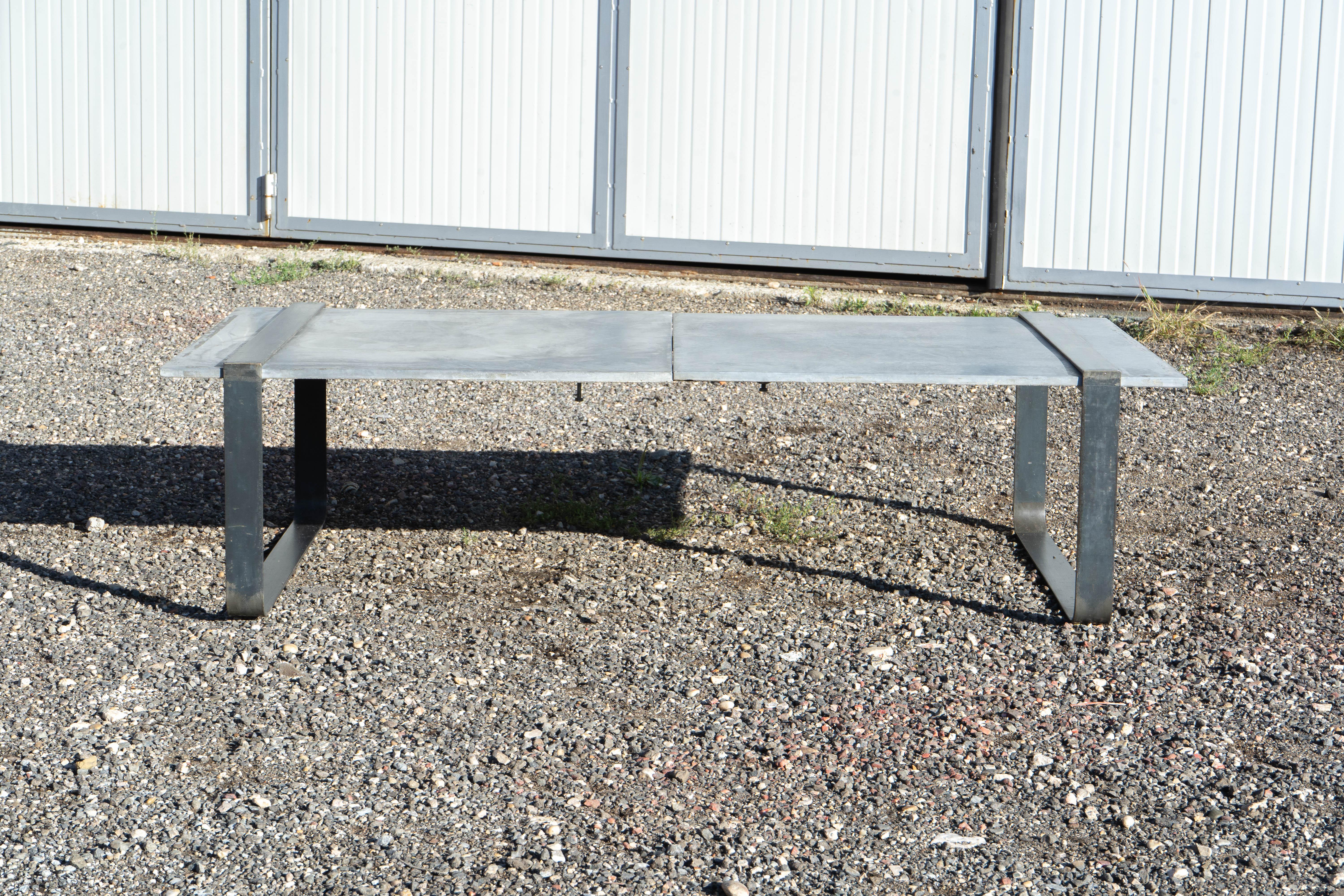 This striking contemporary coffee table embodies industrial minimalism, showcasing a split rectangular top crafted from polished concrete slabs with a subtle veined texture that adds depth and character to any space. The robust steel frame, finished