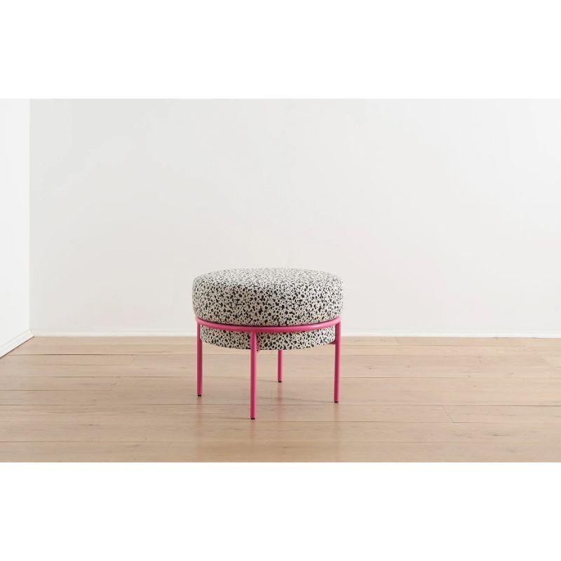This Madda Round Ottoman by Michael Felix is upholstered in a recycled fabric with a black and white inkblot pattern. Its pink metal base wraps around the plump cushion as if to squeeze the cushion full of support and comfort. This is an ottoman