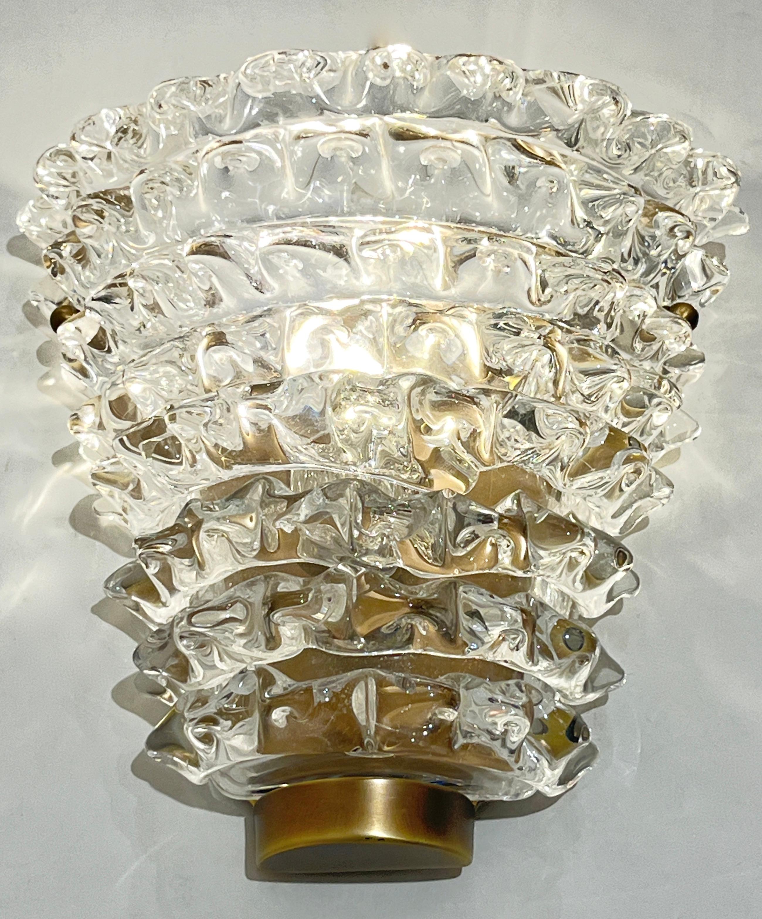 Organic sculpture pair of crystal clear Murano glass wall lights in the style of Barovier Toso, with a cone shape, made using the rostrato technique supported on a antiqued brass hand-made and hand-cut plate.
Options for finishes and glass