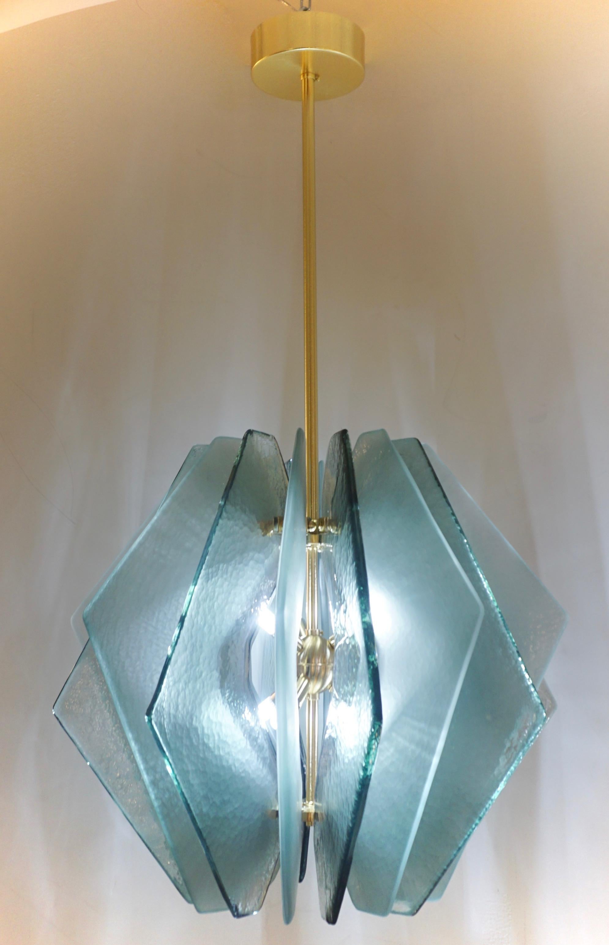 Une suspension moderne, une création entièrement réalisée à la main en Italie avec une forme de lanterne stylisée, dans le style de Max Ingrand, la structure en laiton satiné est décorée tout autour de 16 dalles stylisées en boomerang dans