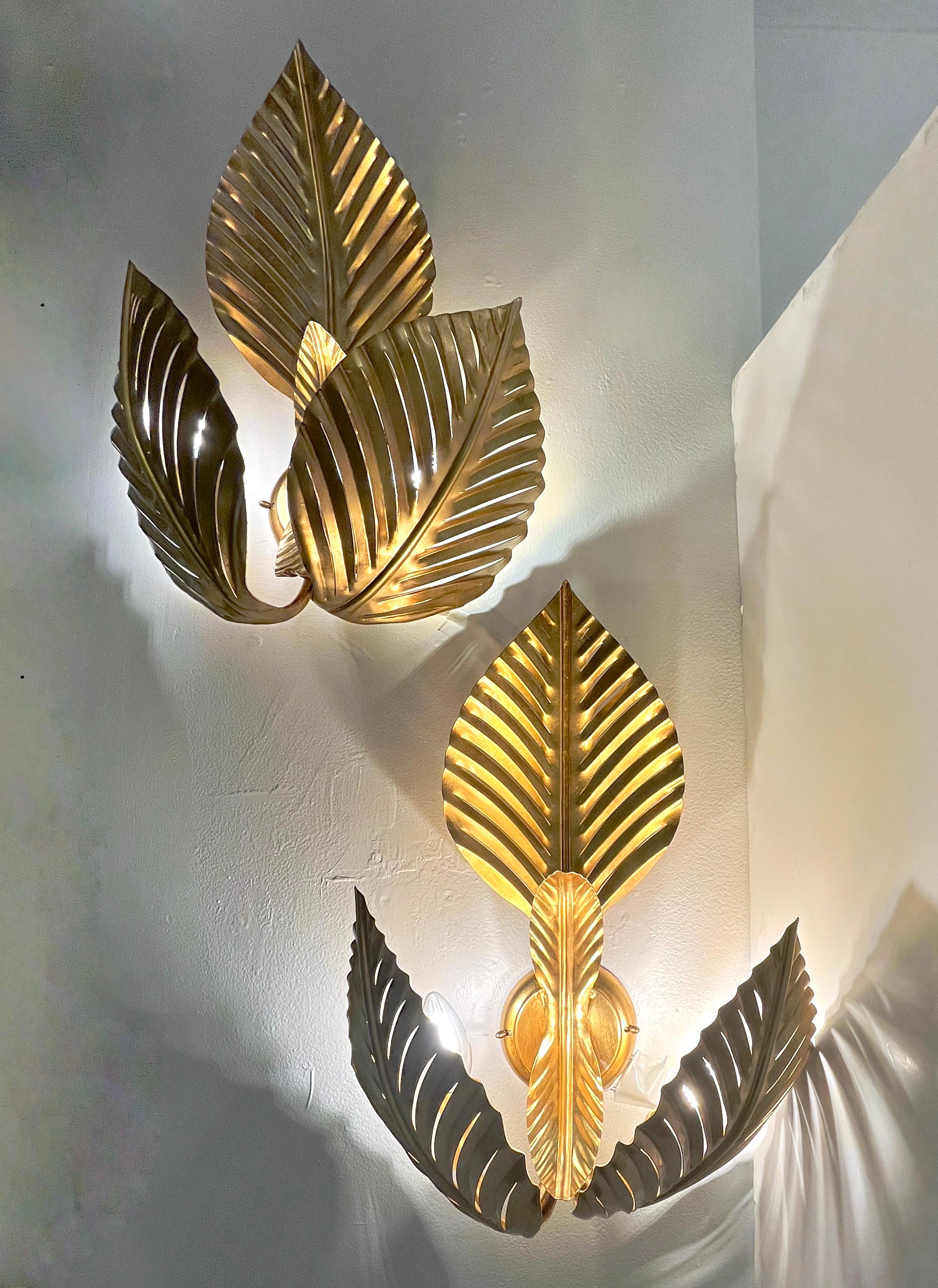 Entirely hand made in Italy, these bespoke wall lights with Hollywood Regency glamour, are composed of 3 Art Deco Design leaves made of hand-gilt iron, supported by a central round back plate. Each leaf is decorated with perforated slits, not only