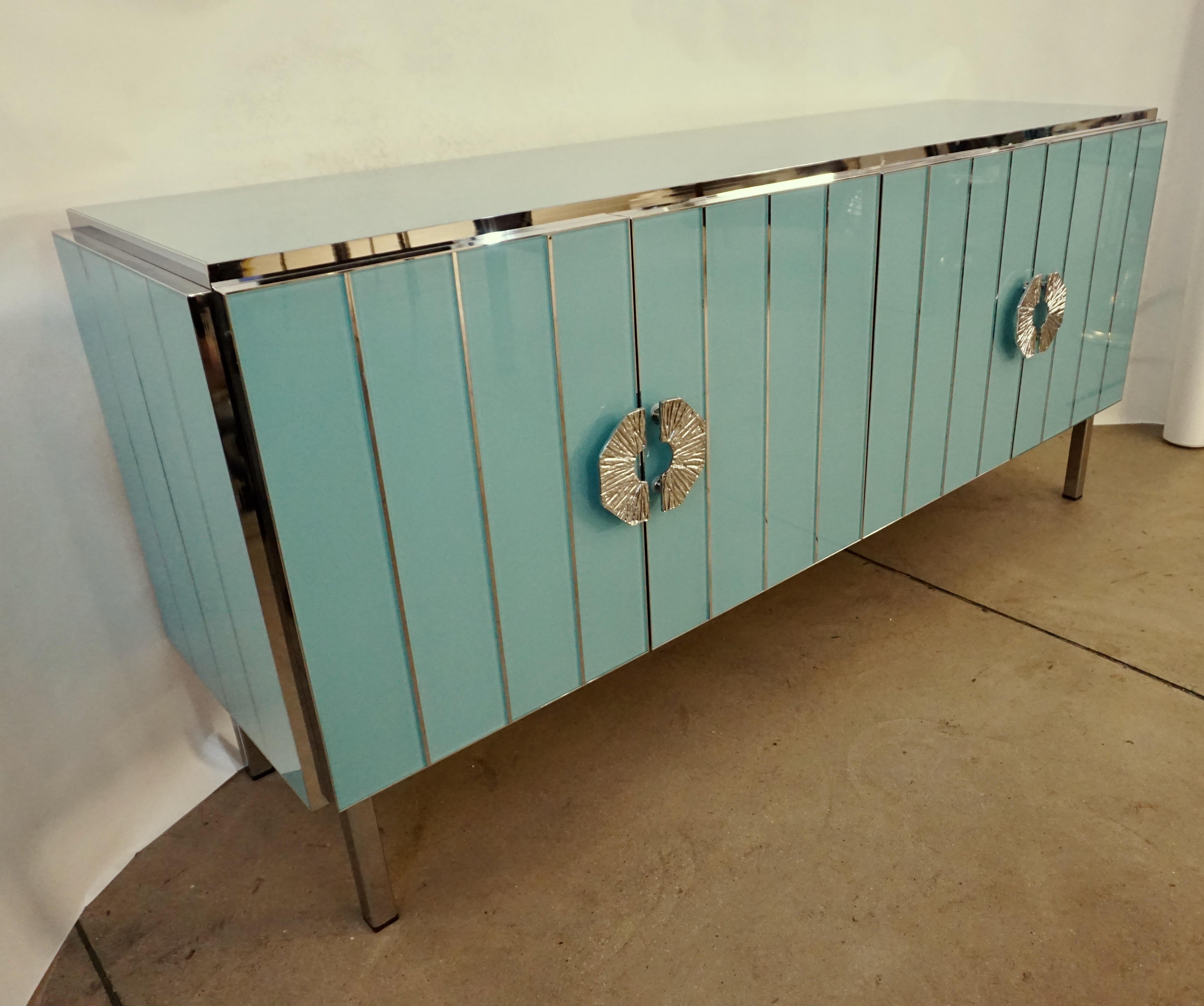 Bespoke customizable 4-door credenza/sideboard entirely handcrafted in Italy with elegant Art Deco style, the surround decorated with art glass in an enticing aquamarine pastel blue, striped with nickel inserts, raised on geometric straight nickel