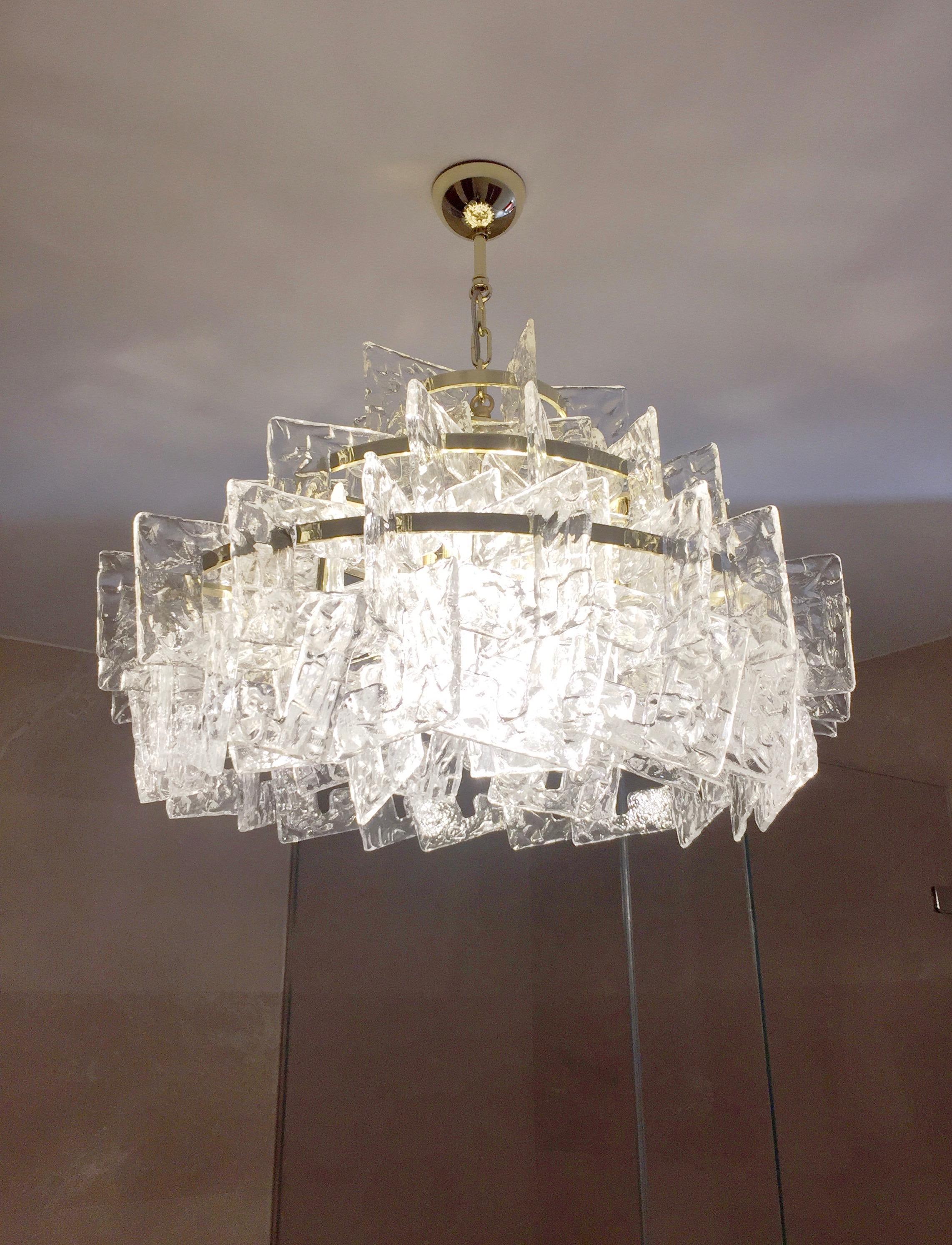 A Venetian very elegant bespoke chandelier, entirely handcrafted in Italy. The handmade 3-tier structure in gold brass presents an organic mesh modern decor with a couture interlaced design composed of sophisticated interlocking links in crystal