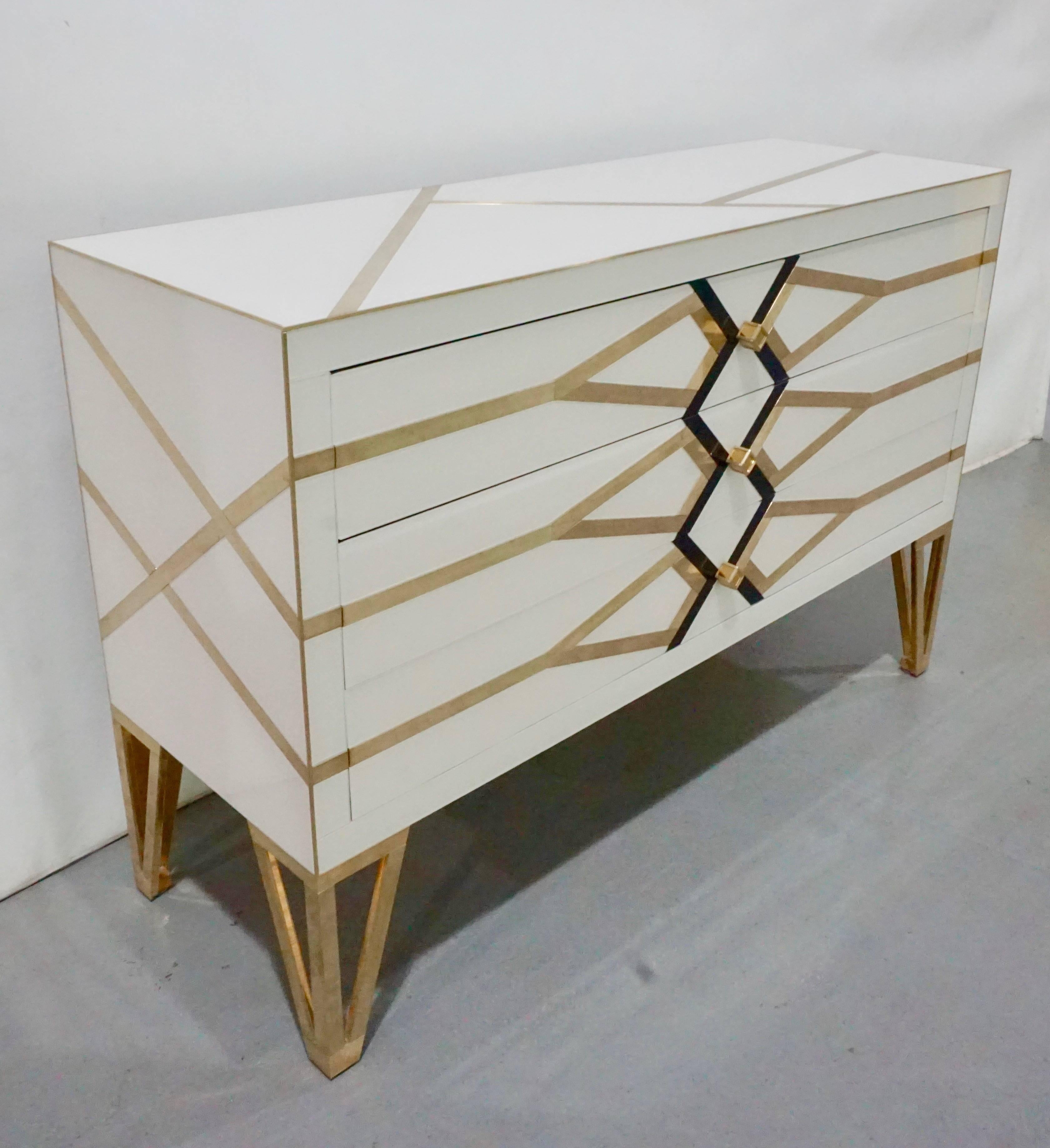 Italian three-drawer customizable commode / sideboard, entirely handmade, exclusive modern Art Deco design by Cosulich Interiors, showing high quality and elegance of execution: the surround in ivory white is decorated with a geometric architectural