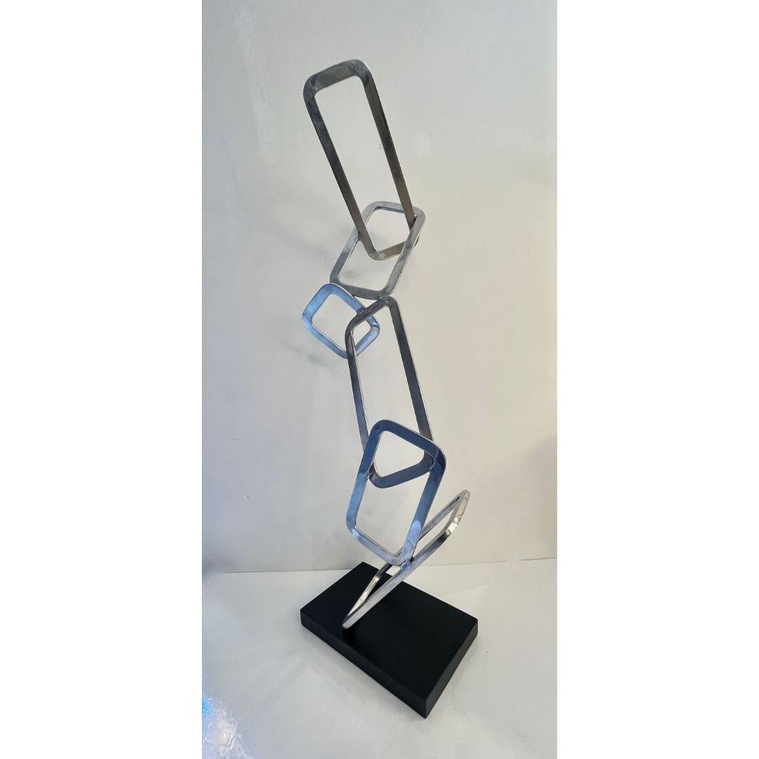 Exclusive abstract Work of Art entirely hand-crafted in Italy in aluminum with a polished finish. This post-modern design defies gravity with its interlocking open rectangles in different sizes. Raised on a black lacquered base. Signed Fp Art with