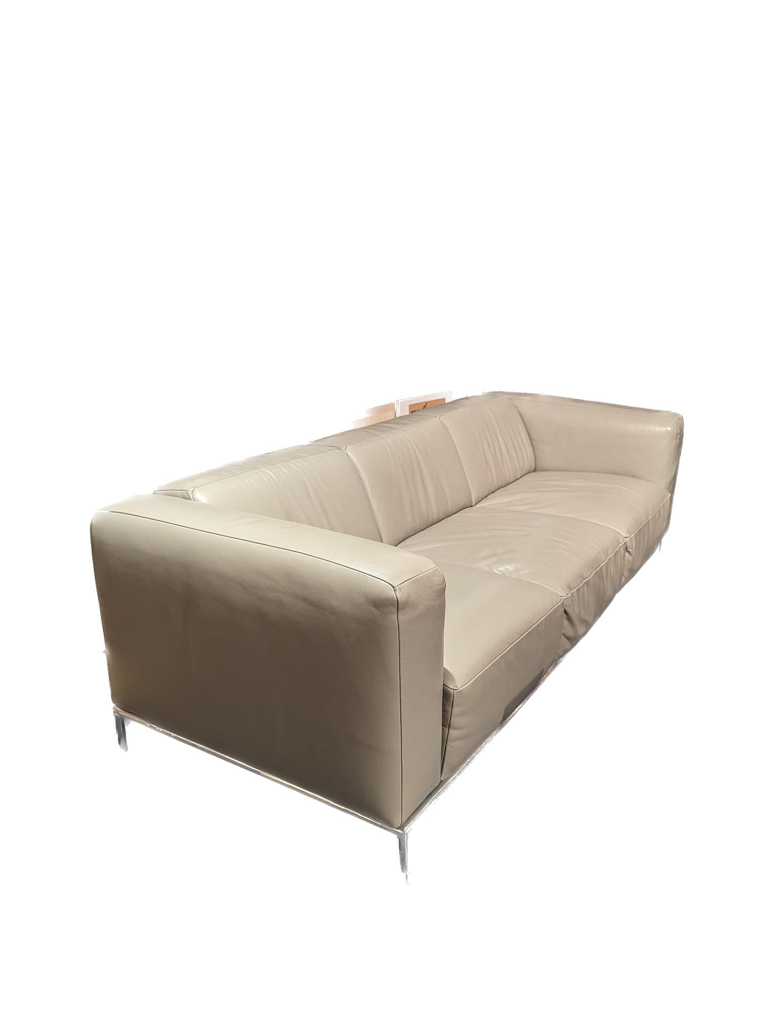 Offered is a contemporary greige leather upholstered sofa purchased at Bloomingdale's. It was made in Italy. 

It measures 89