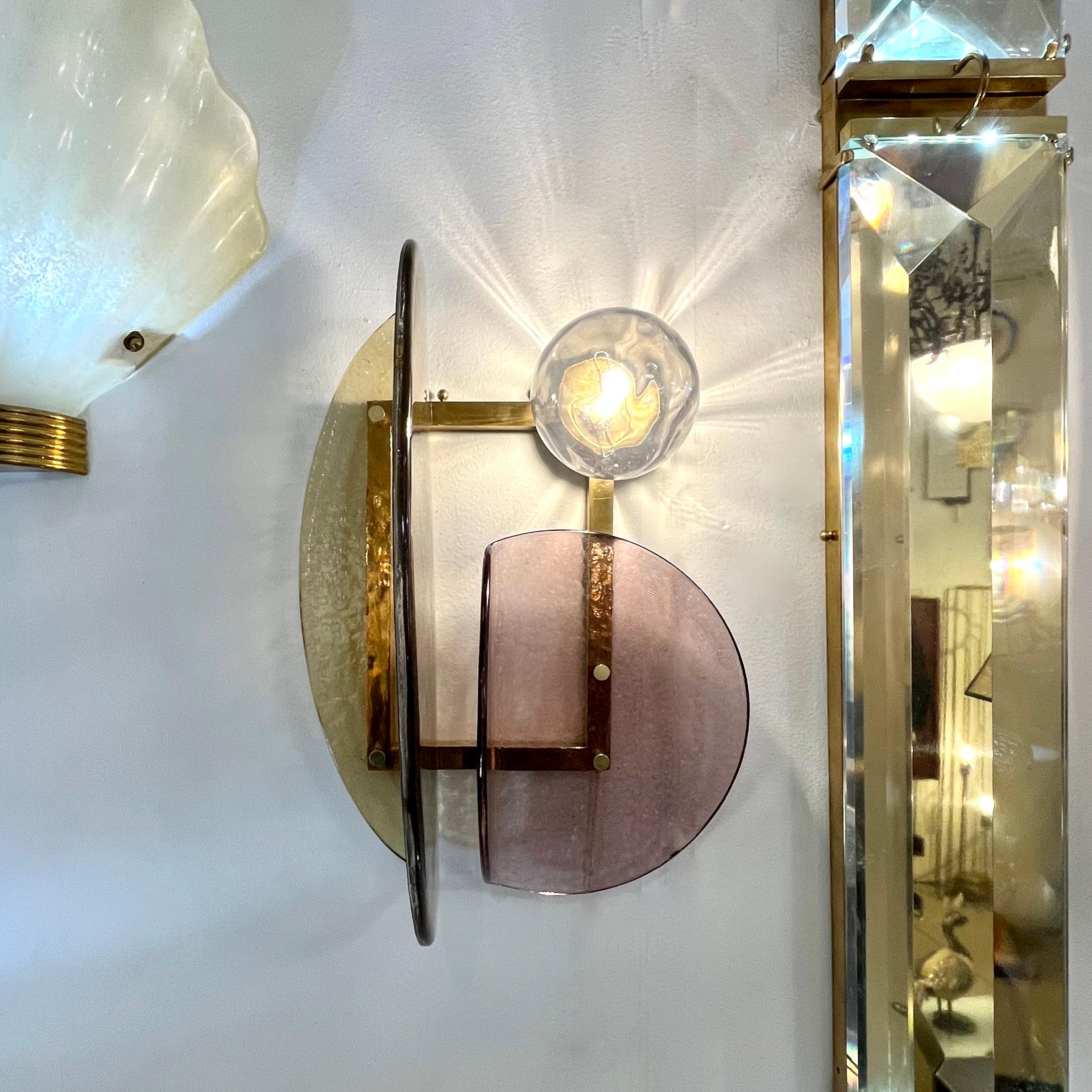 A contemporary creation with a unique modern geometric design, this wall light is entirely handcrafted in Italy. The molded textured glass elements of organic rounded shape, in amber gold and pastel crimson Murano glass, are mounted in a geometric