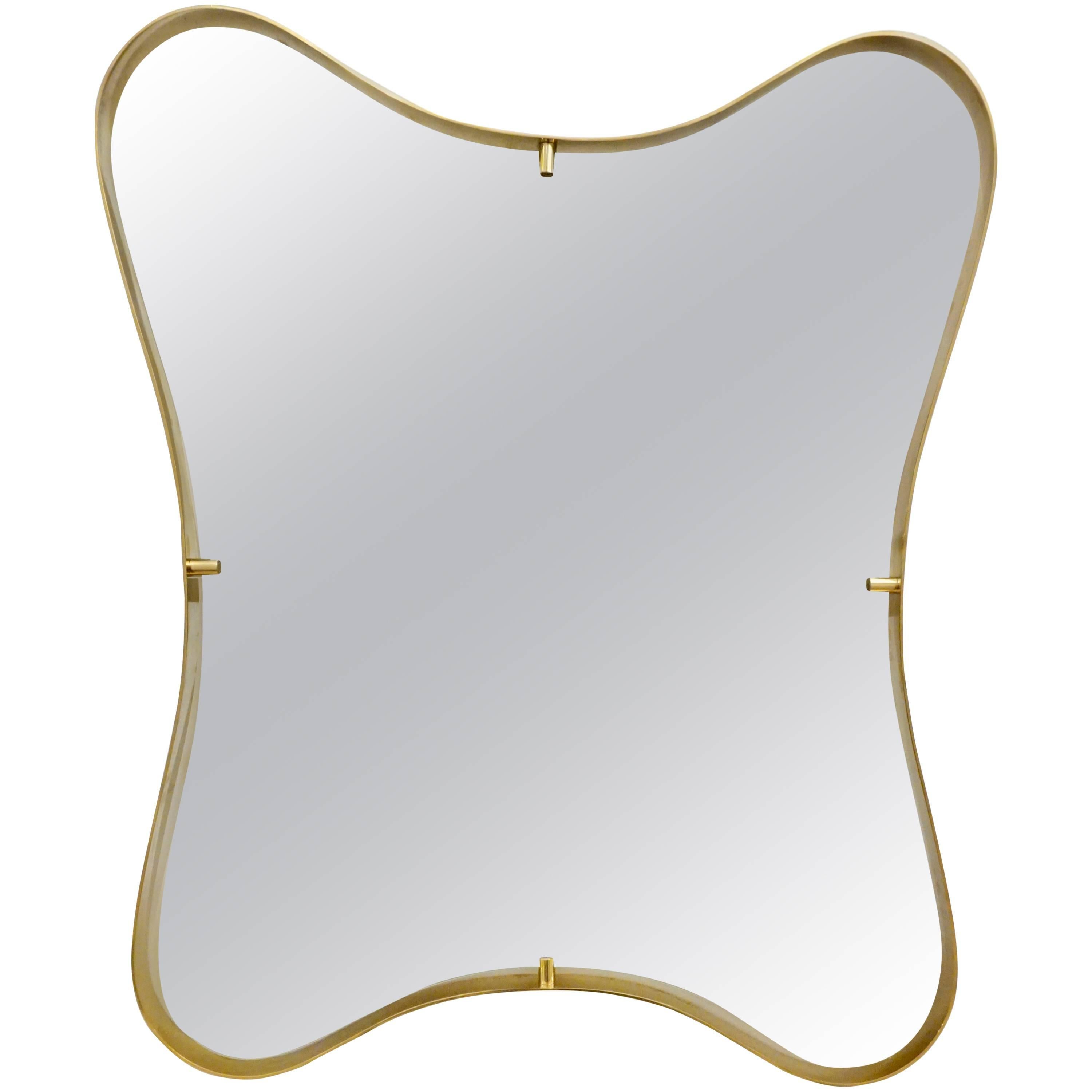 Contemporary Italian modern design mirror with elegant curved brass frame detached from the mirror, entirely handcrafted, showing a sensual smooth wavelike motion design.
The mirror ends in a slight bevelled rounded edge and shows high quality of
