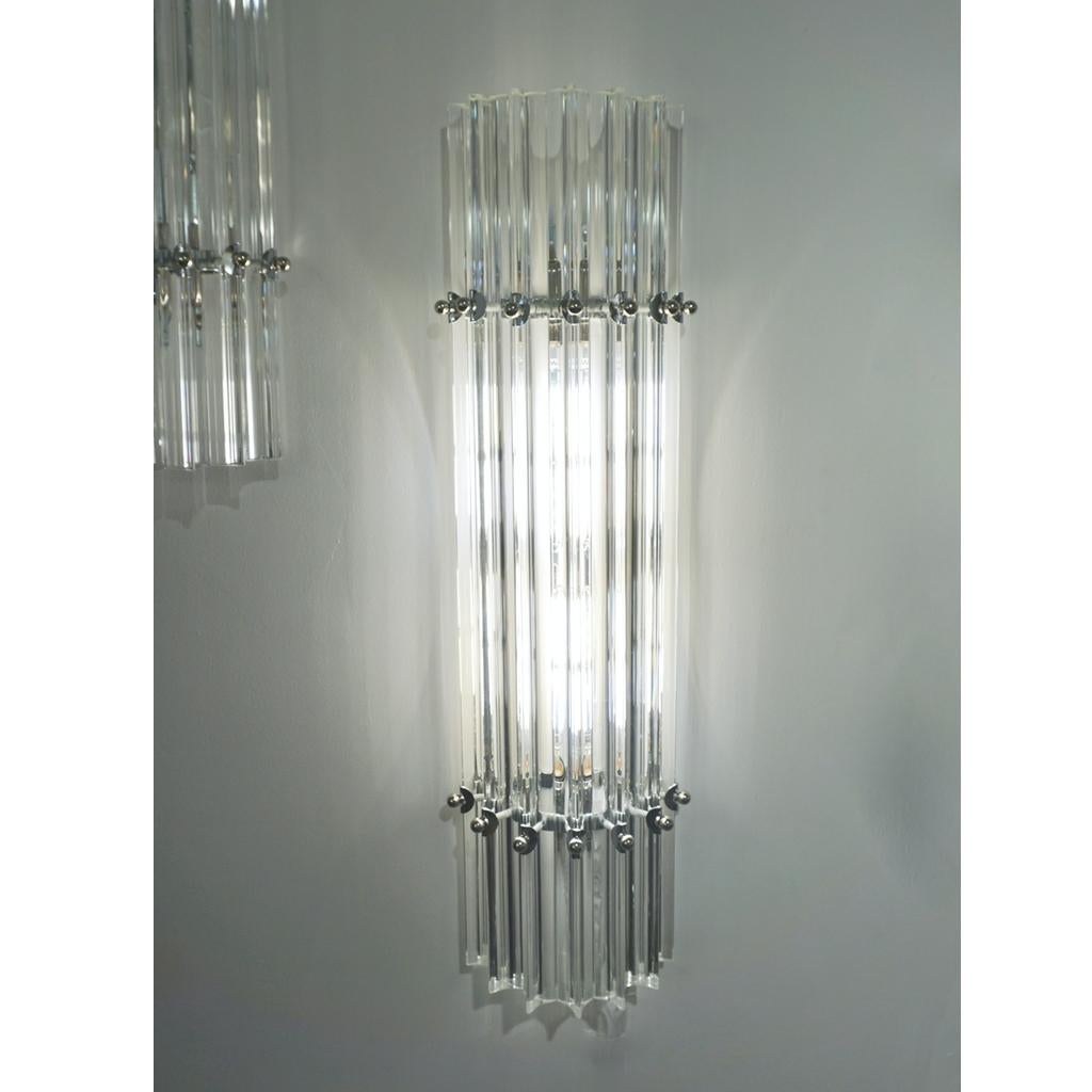 Very sleek custom Venetian wall light with organic minimalist design, consisting of seven straight crystal clear Murano glass rods of triangular section with amazing concave sides, that not only highlight the curved design but amplify the light