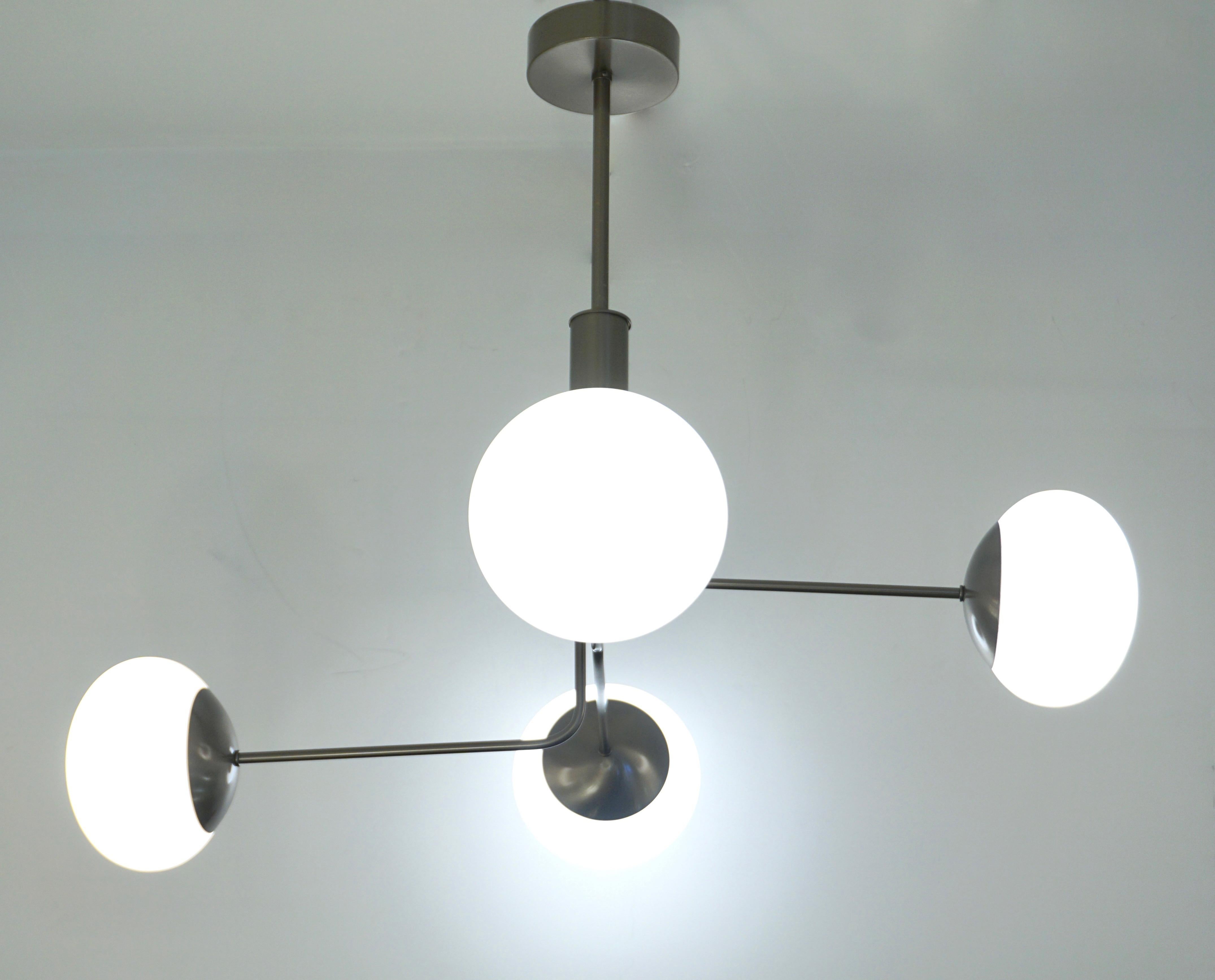 A minimalist Italian structural lighting fixture in an organic Mid-Century Modern design, entirely handcrafted recalling Gino Sarfatti style. The asymmetrically positioned four ovoid globes in white opaline Murano glass give an interesting movement