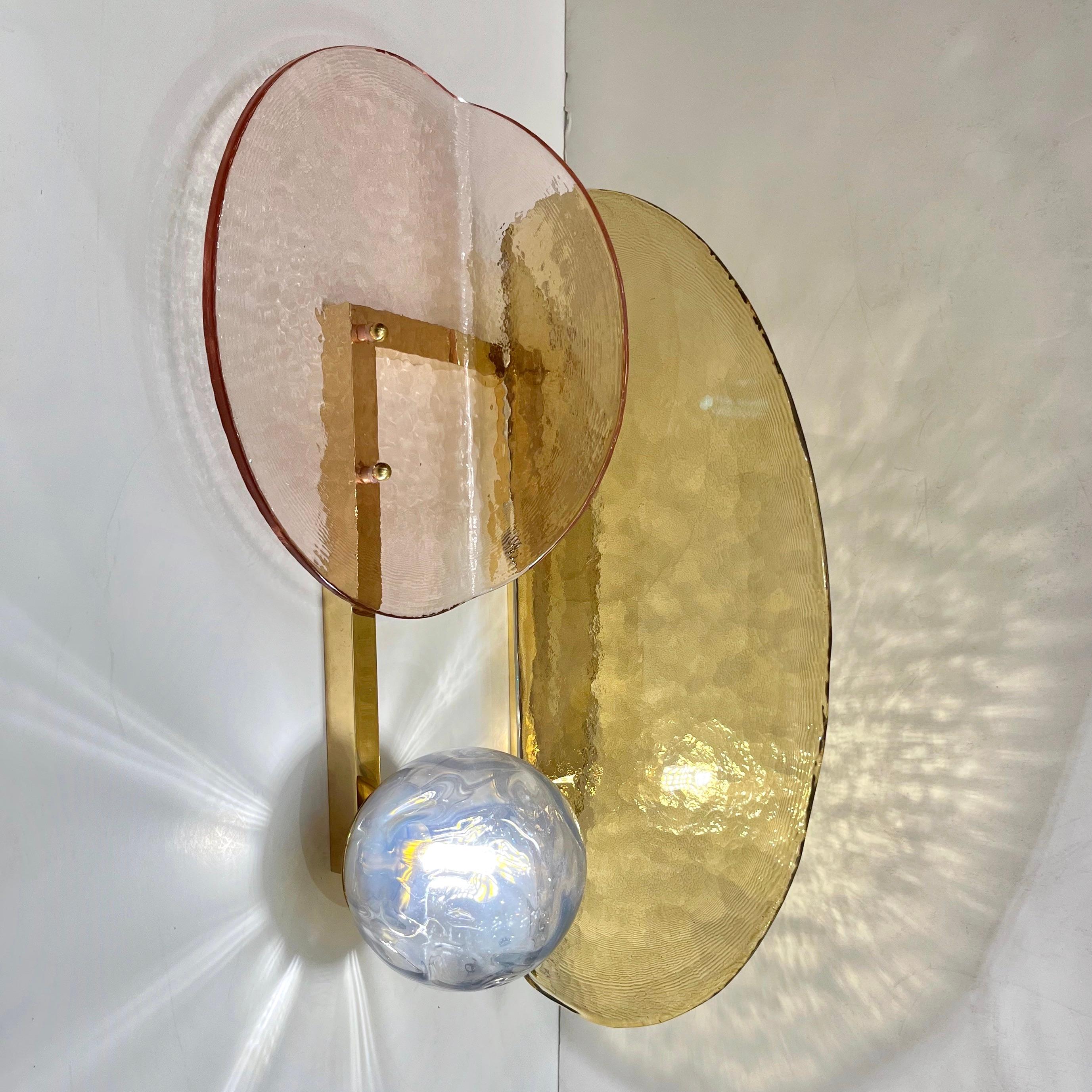 A contemporary creation with a unique modern geometric design, these wall lights are entirely handcrafted in Italy. The molded textured glass elements of organic curved shape, in amber gold and light pink, daisy rose Murano glass, are mounted in a