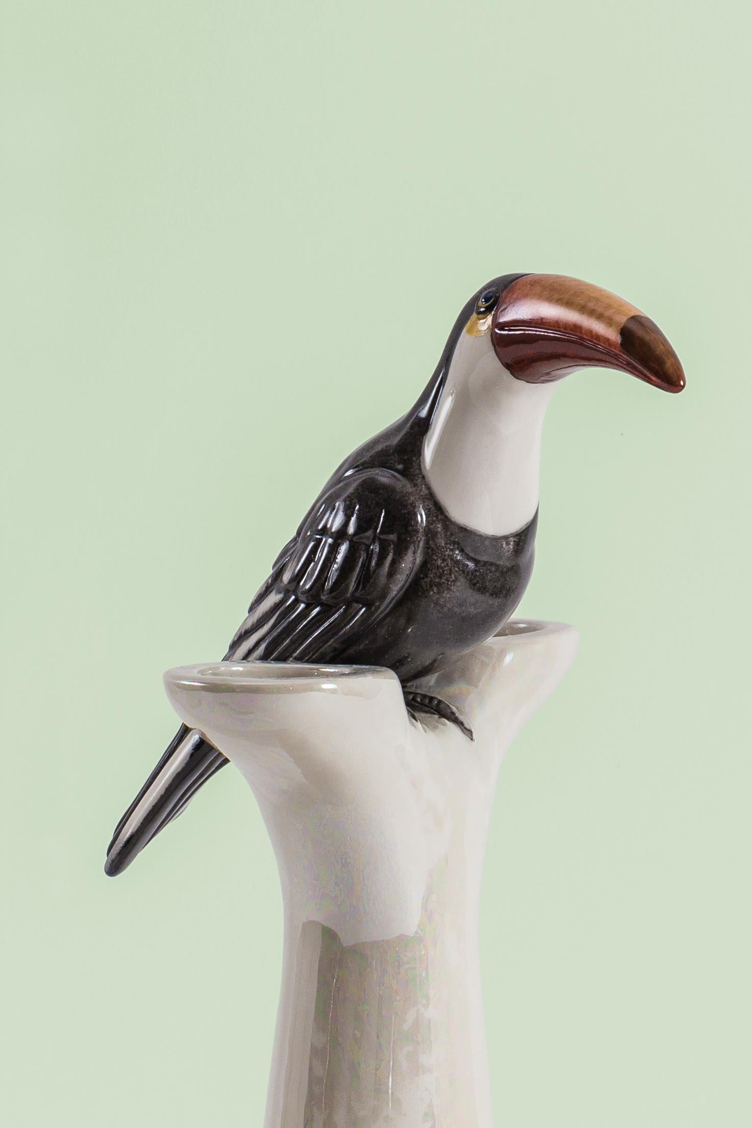 This Italian porcelain sculpture is part of Grand Tour by Vito Nesta. Made in Capodimonte porcelain with a glossy and iridescent finish. this double candle holder is embellished by a hand painted toucan.
