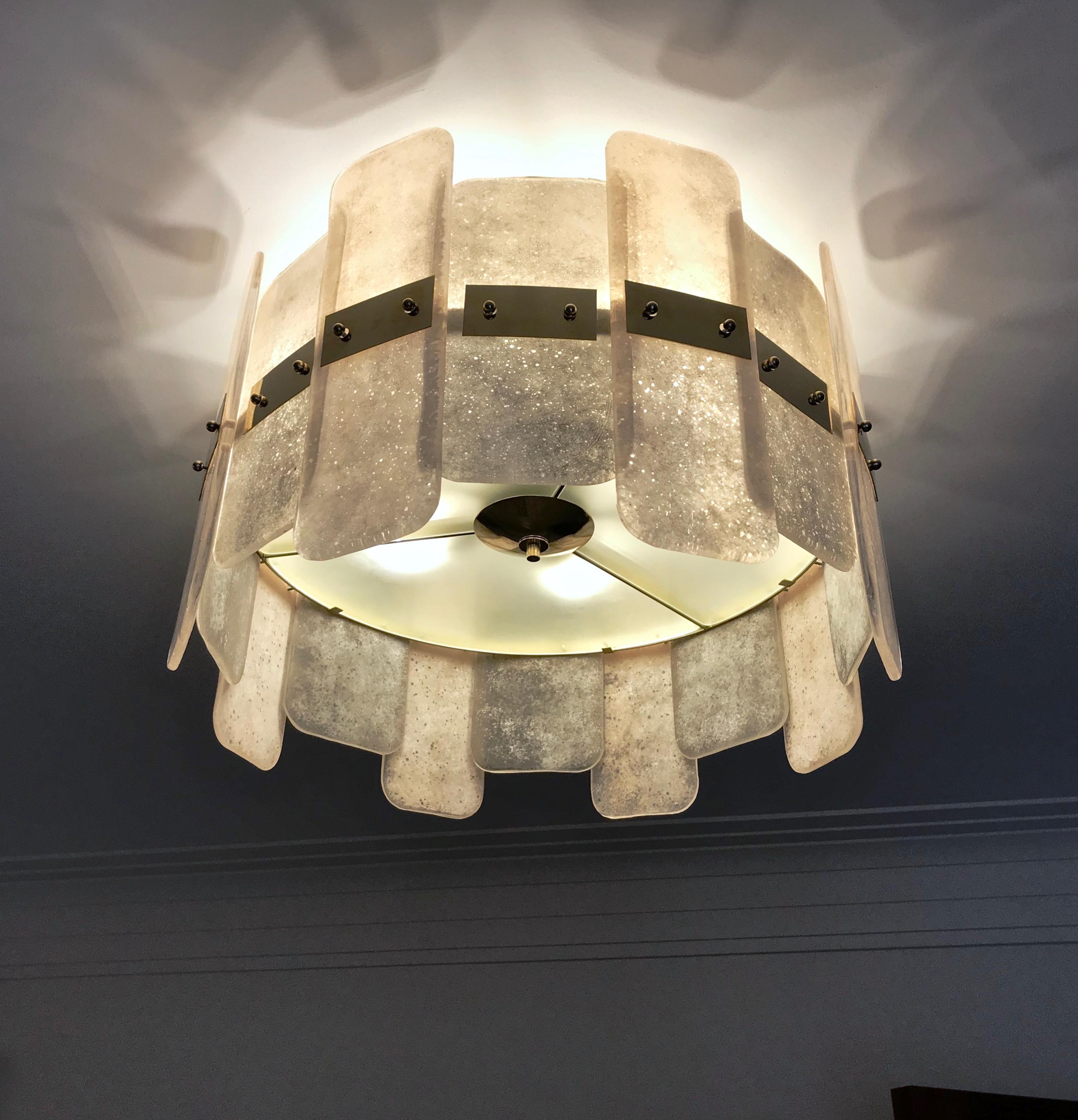 A contemporary Italian bespoke modern chandelier with Art Deco Design, entirely handcrafted in Italy, customizable as flushmounts or pendants with different glass colors and finishes, here with a brass structure in a geometric circular shape, with a